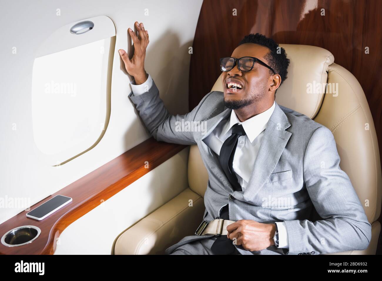uomo d'affari africano americano che tiene la cintura di sicurezza e soffre di  attacchi di panico durante il volo su un aereo privato Foto stock - Alamy