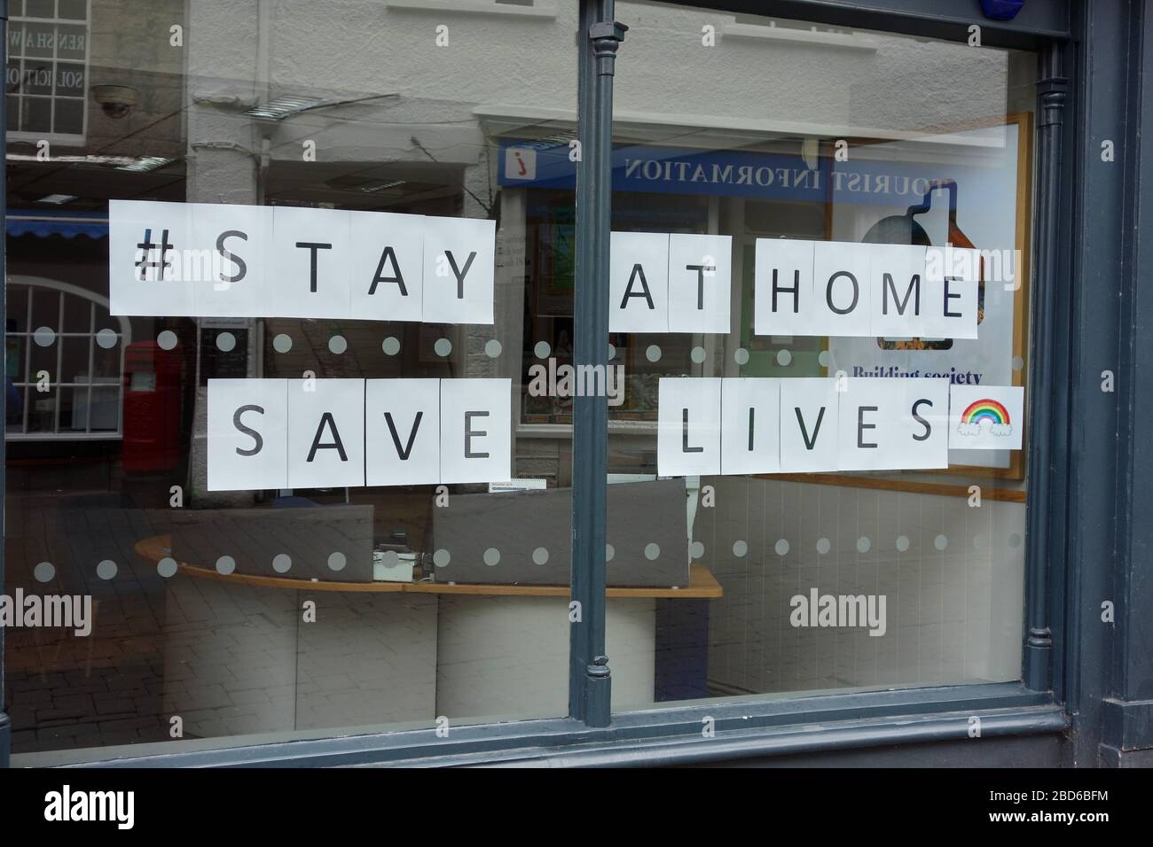 Vetrina con lo slogan "Stay at Home, Save Lives" nella vetrina come riferimento al Coronavirus nel Regno Unito Foto Stock