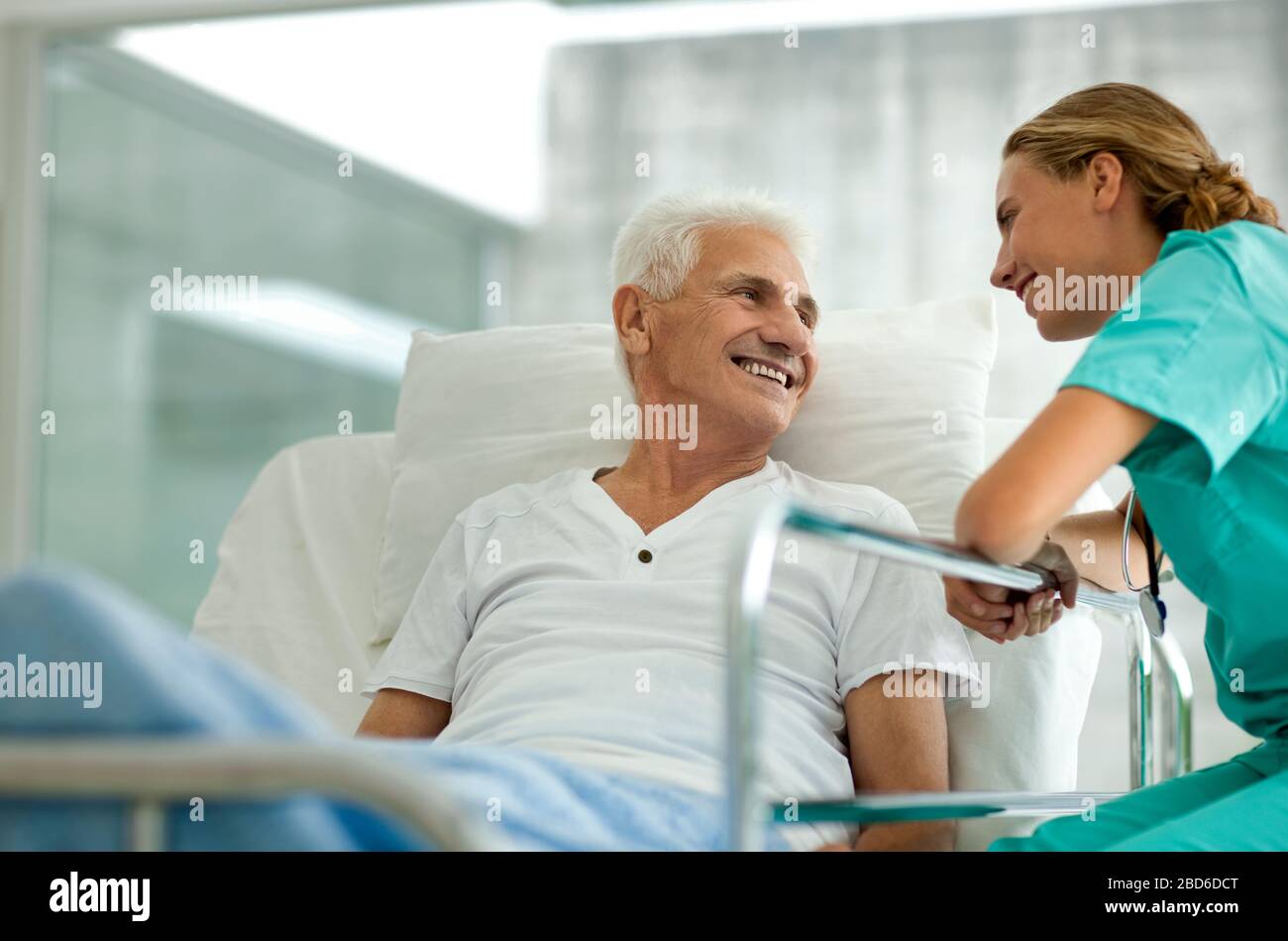 Ritratto di un anziano uomo nel letto di un ospedale e un giovane medico donna. Foto Stock