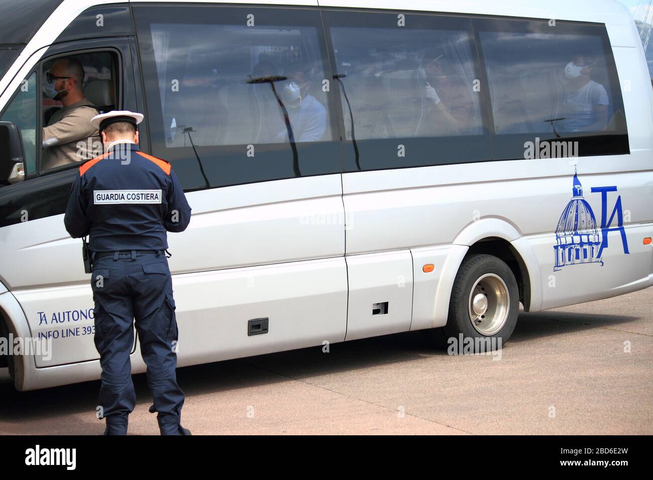 Gli uomini sbarcati dalla nave che li ha riportati in Italia dalla Tunisia sono trasportati su un autobus privato per raggiungere le loro case e sono controllati Foto Stock