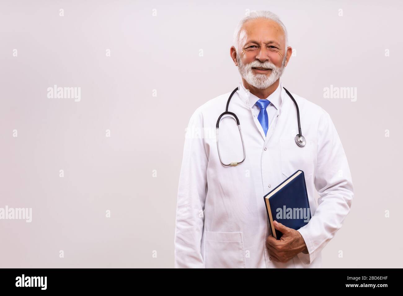 Ritratto di medico senior con organizzatore personale su sfondo grigio. Foto Stock