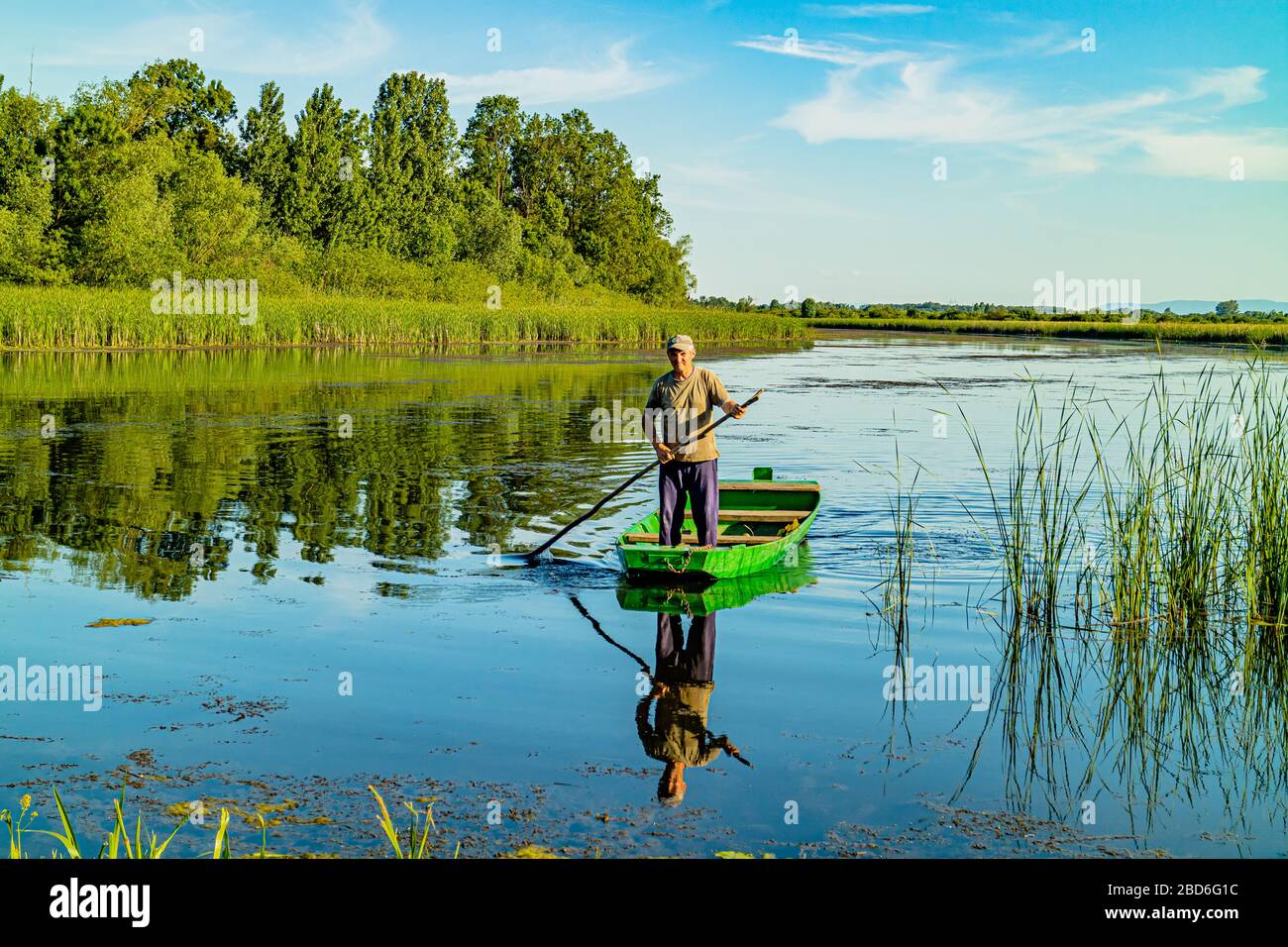 Un uomo serbo che spinge una barca o una zattera tradizionale sul fiume Zasavica, parco naturale nazionale di Zasavica, Serbia, Europa. Maggio 2017. Foto Stock