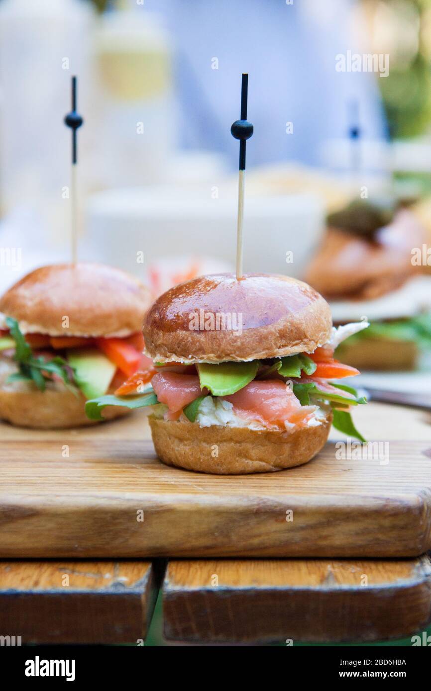 Hamburger con formaggio spalmabile, salmone salato, cale, avocado su panino di grano. Sfondo rustico. Foto Stock