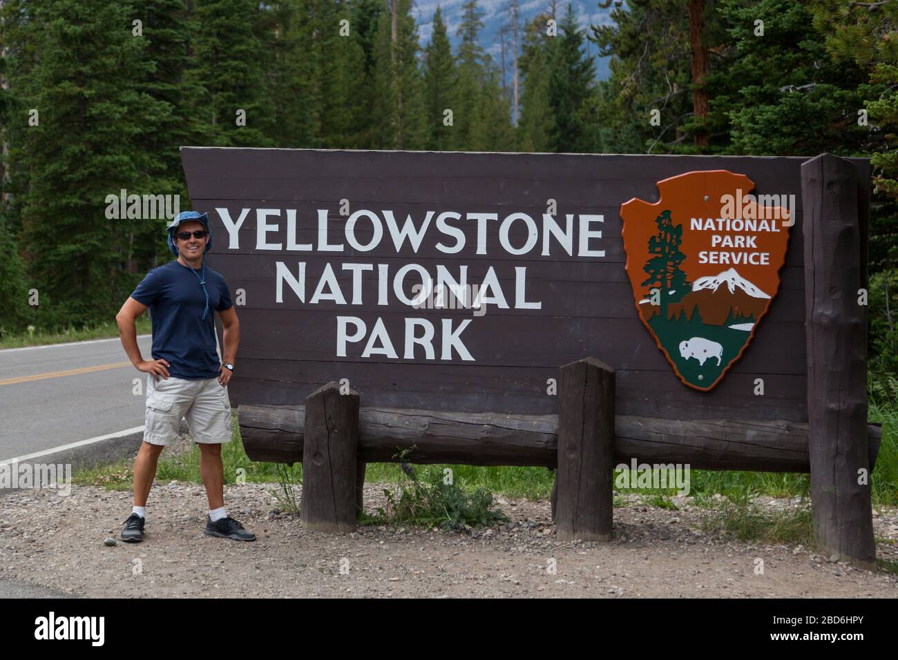 Yellowstone National Park, Montana, USA - 13 luglio 2014: Un giovane turista si trova accanto a un cartello in legno per Yellowstone National Park all'interno del nord-est Foto Stock