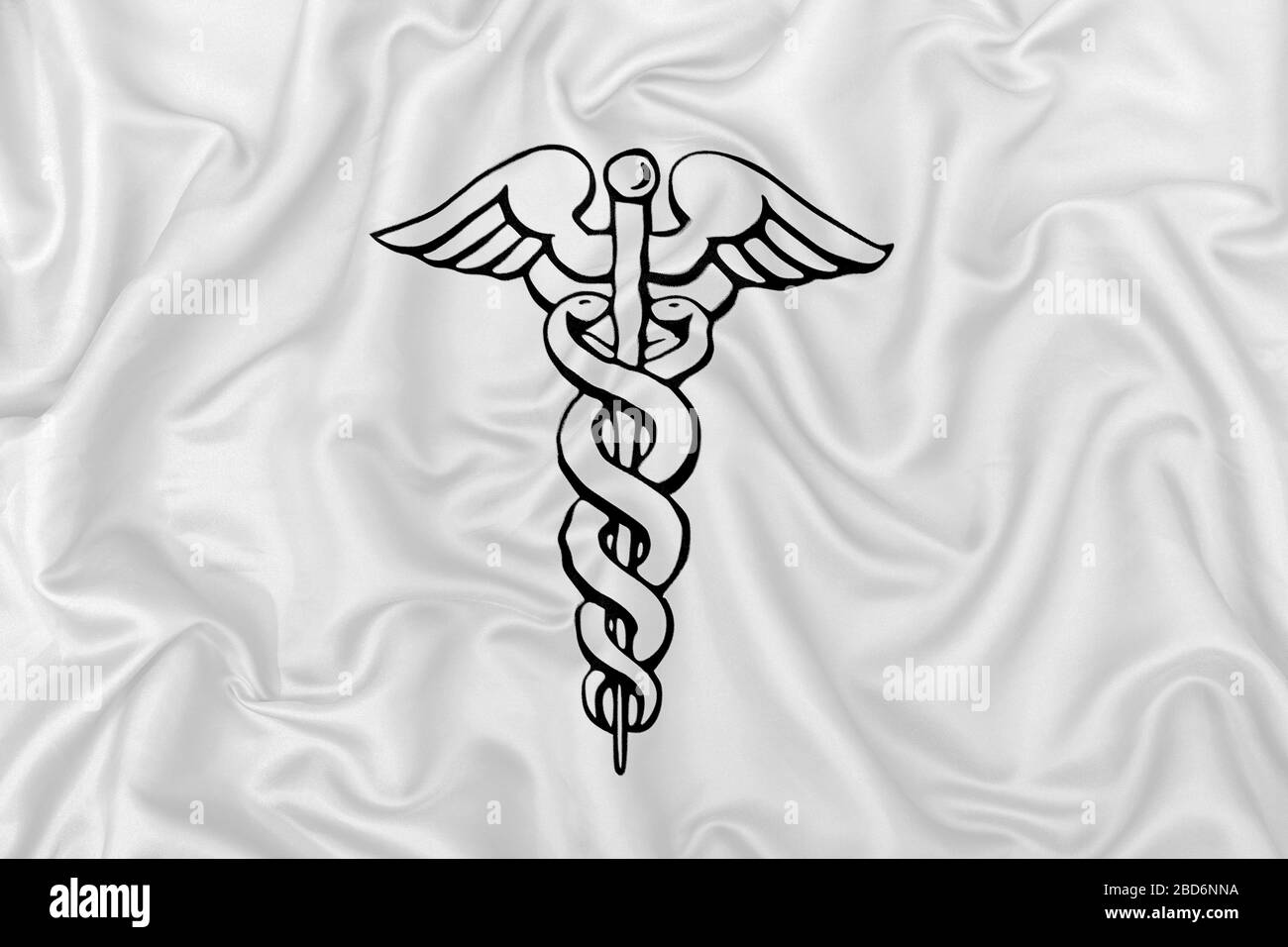 Caduceus simbolo medico su tessuto satinato di seta bianca. Foto Stock