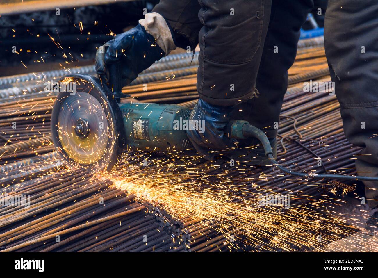 Izhevsk, Russia-Aprile 06.2020: Lavoratore con smerigliatrice angolare Makita taglia le barre d'acciaio Foto Stock