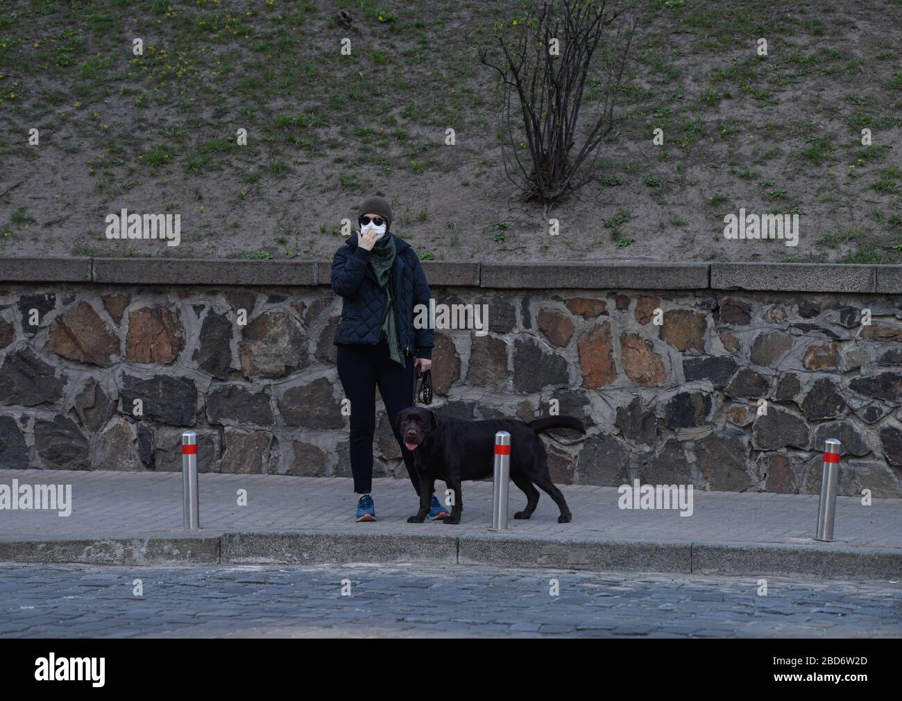 Aprile 6, 2020, Kiev, Ucraina: Una donna cammina il suo cane vicino a Mariinsky Park indossando una maschera facciale come misura preventiva, durante la pandemia del virus corona. Il Gabinetto dei ministri dell'Ucraina ha adottato una risoluzione sul rafforzamento delle misure di quarantena. Il governo vieta di riunirsi per le strade in gruppi di più di due persone, di camminare nei parchi, nelle aree del parco forestale e nei terrapieni, di visitare sport e parchi giochi. (Credit Image: © Maksym Polishchuk/SOPA Images via ZUMA Wire) Foto Stock