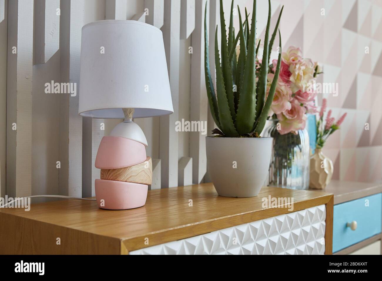 soggiorno. lampada e fiore in vaso su una cassettiera in camera. Decorazione interna. Foto Stock