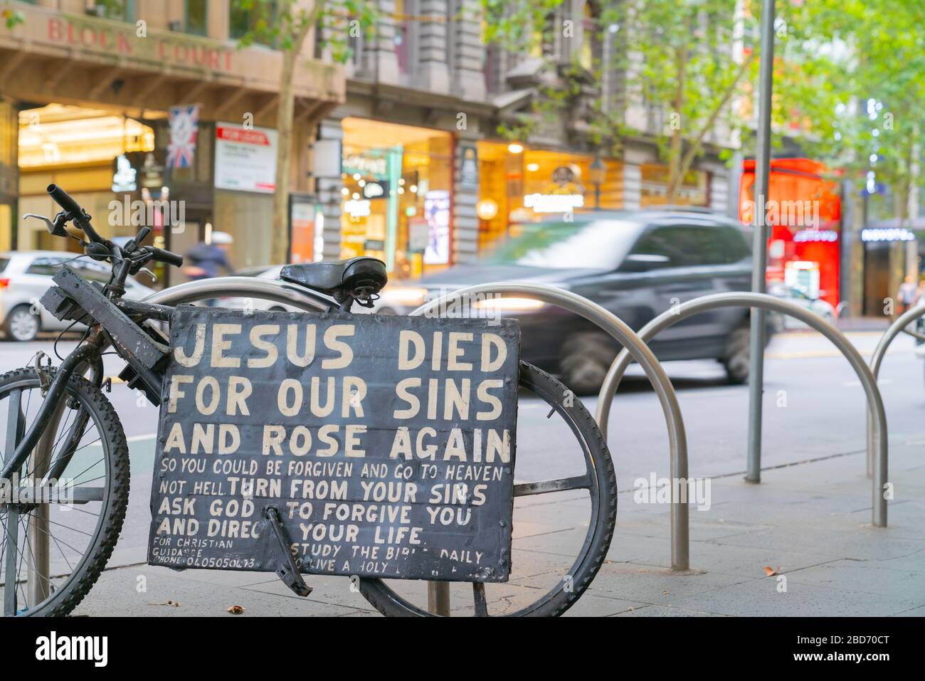 Melbourne Australia - Marzo 14 2020; credenze religiose, segno religioso sulla lavagna fissato in bicicletta sulla strada della città con veicoli sfocati che passano in Foto Stock