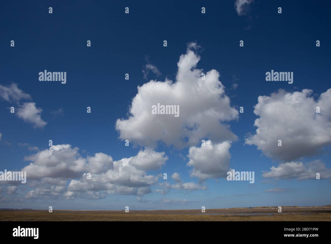 Una vista sulle paludi saline verso Blakeney Point da Morston, Norfolk, Inghilterra, mostrando i "grandi cieli" tipici della zona con il cielo delle nuvole di cumulus. Foto Stock