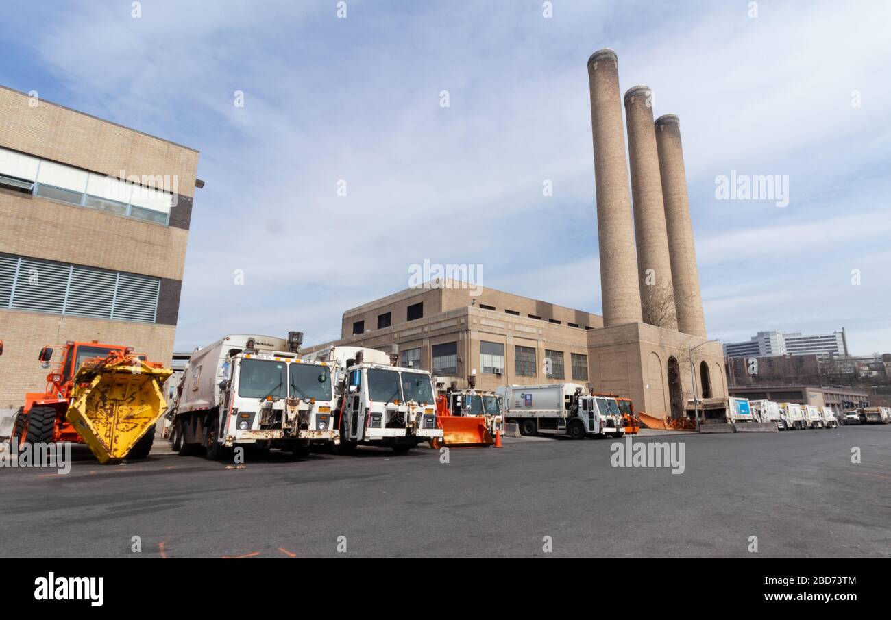 Vari tipi di camion per la rimozione di rifiuti e neve allineati in un deposito del Dipartimento di igiene della Città di New York Foto Stock