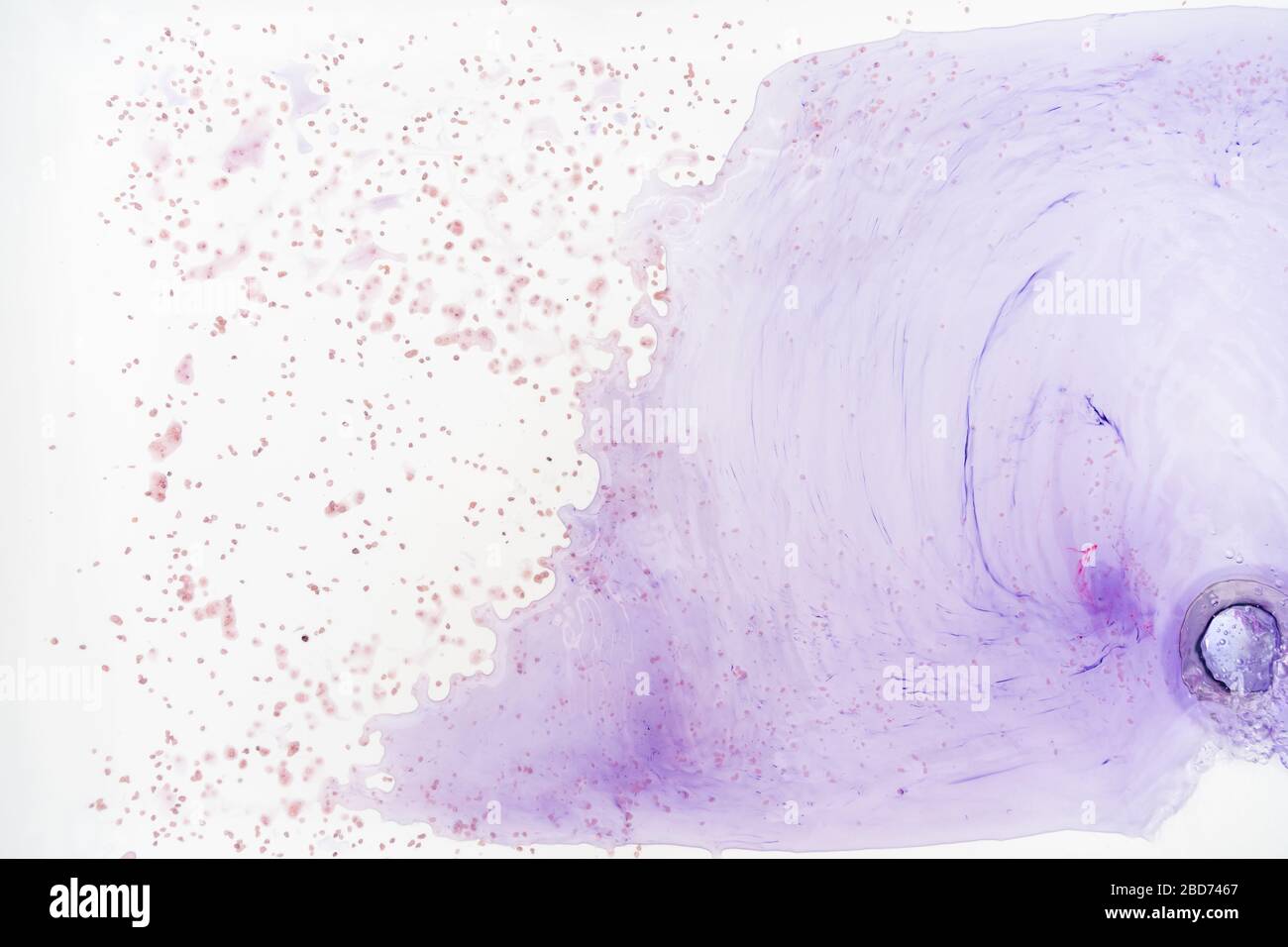 Le macchie blu del colorante nella vasca bianca si sciolgono in acqua Foto Stock