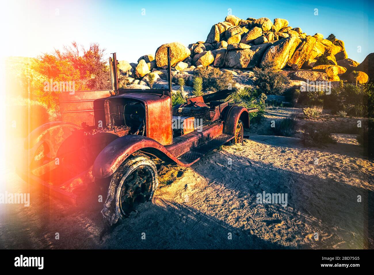 Un'auto abbandonata nel deserto. Joshua Tree National Park, California, USA. La fotografia è stata elaborata con un metodo di perdite di luce per un effetto vintage. Foto Stock
