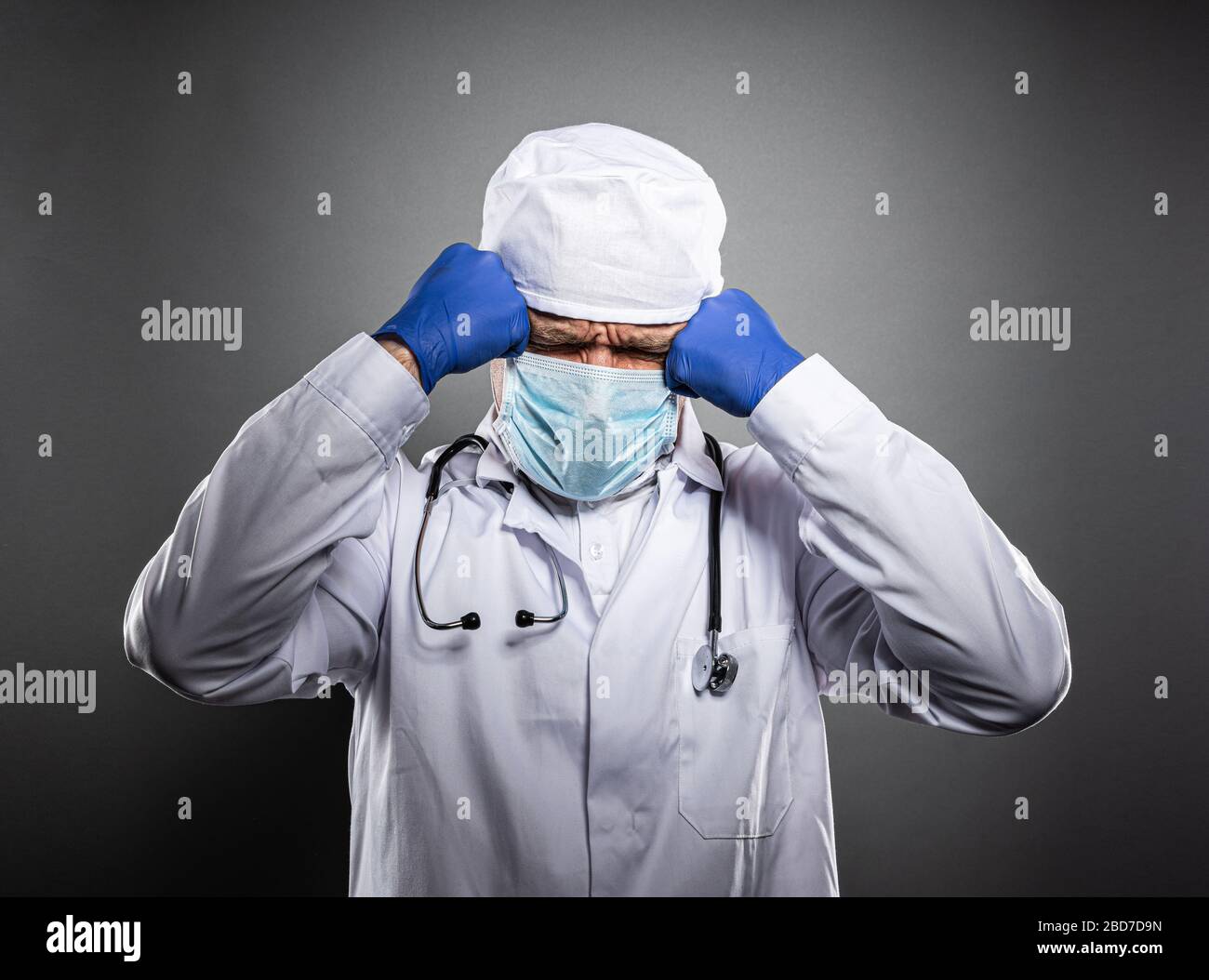 Medico stanco lavorato in uniforme bianca e maschera medica. Foto Stock