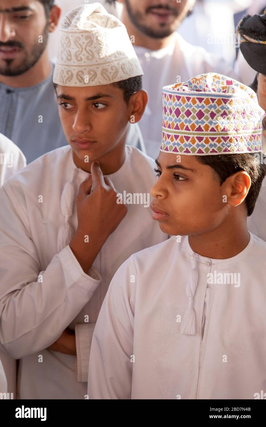 Uomini e ragazzi di Omani apprendisti e si contrattano per il bestiame al mercato del bestiame del venerdì nell'antico suk di Nizwa in Oman Foto Stock