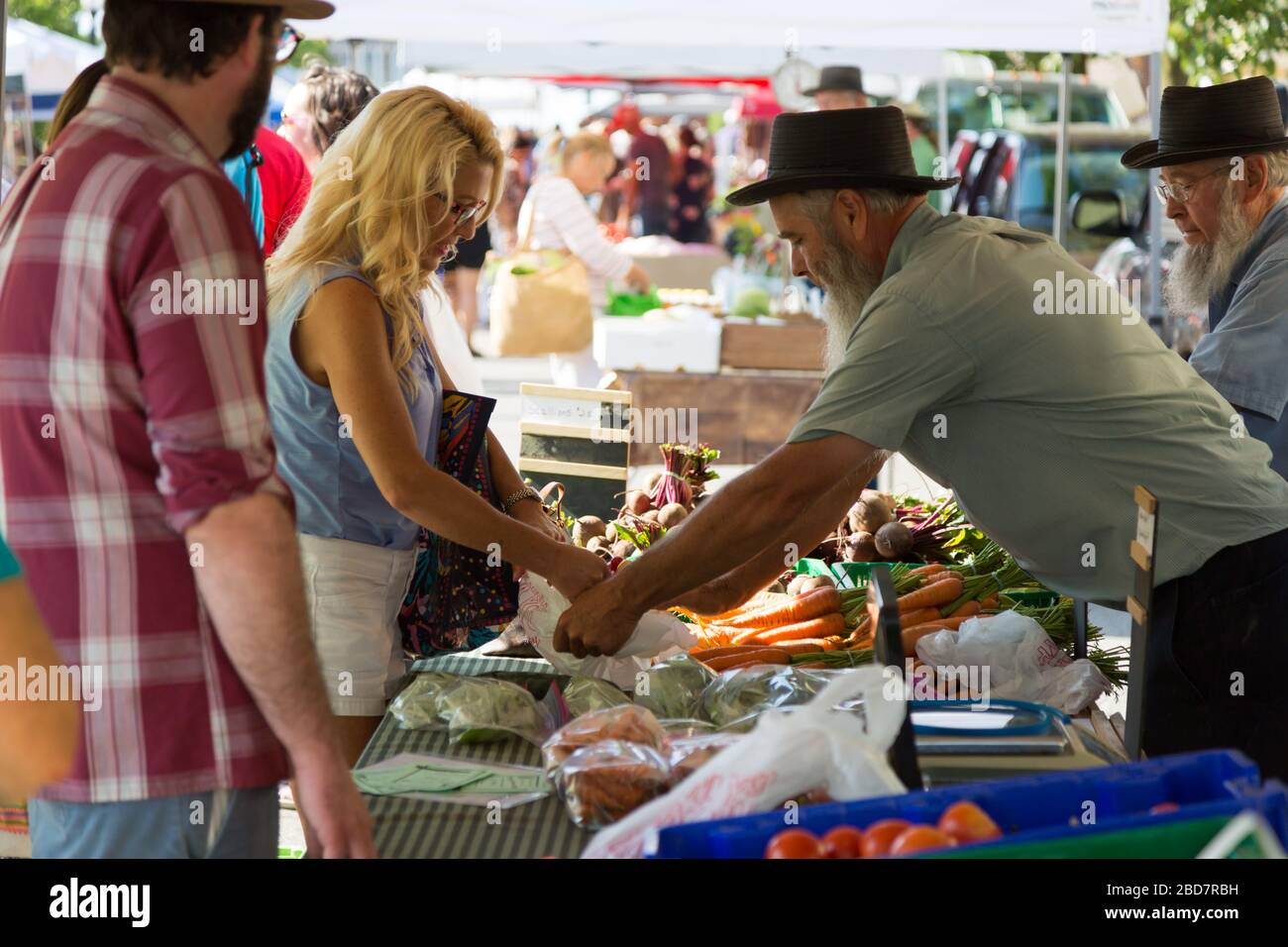 Una donna acquista prodotti freschi da un venditore Amish al mercato agricolo di Fort Wayne nel centro di Fort Wayne, Indiana, USA. Foto Stock