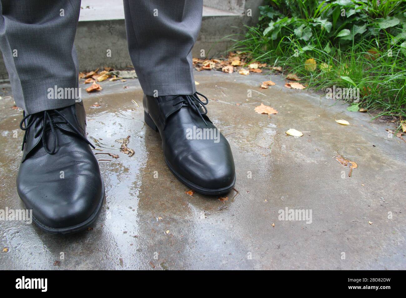 Gambe uomo in stivali neri con lacci sul bagnato Foto stock - Alamy
