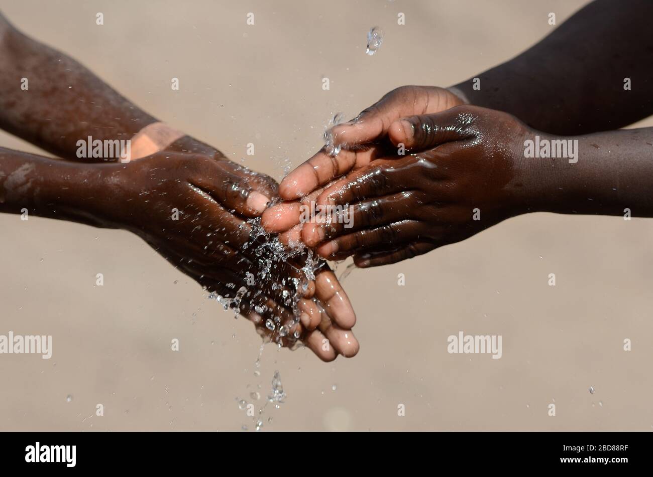Due bambini africani che lavano le mani che sanitano le dita per evitare la  contaminazione di virus, batteri o malattie Foto stock - Alamy