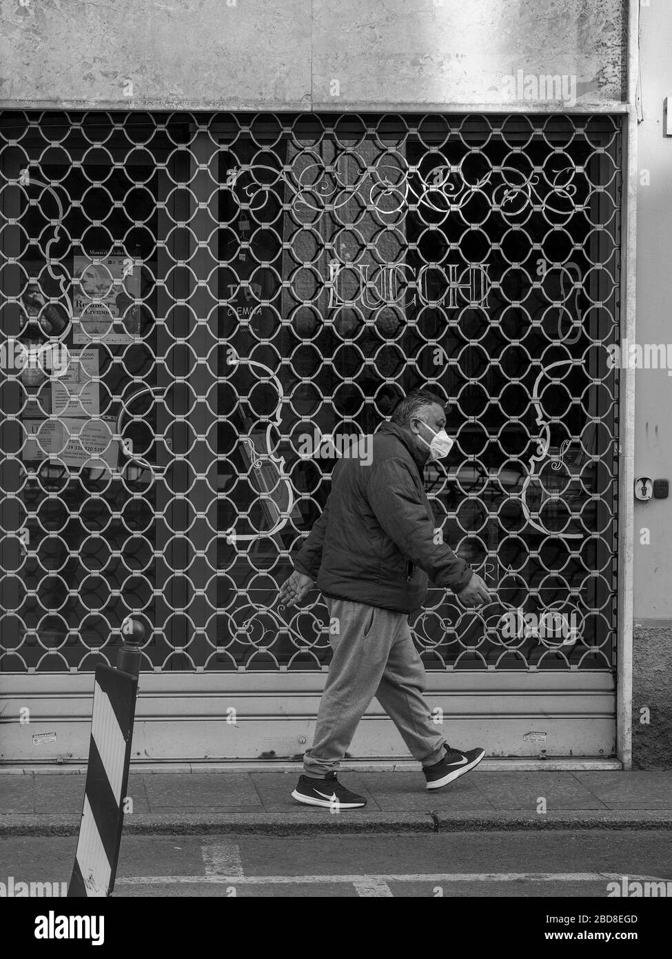 Poche persone non identificate nelle strade vuote durante il blocco del 2020 e lo scoppio a Cremona, in Italia, sotto quarantena Foto Stock