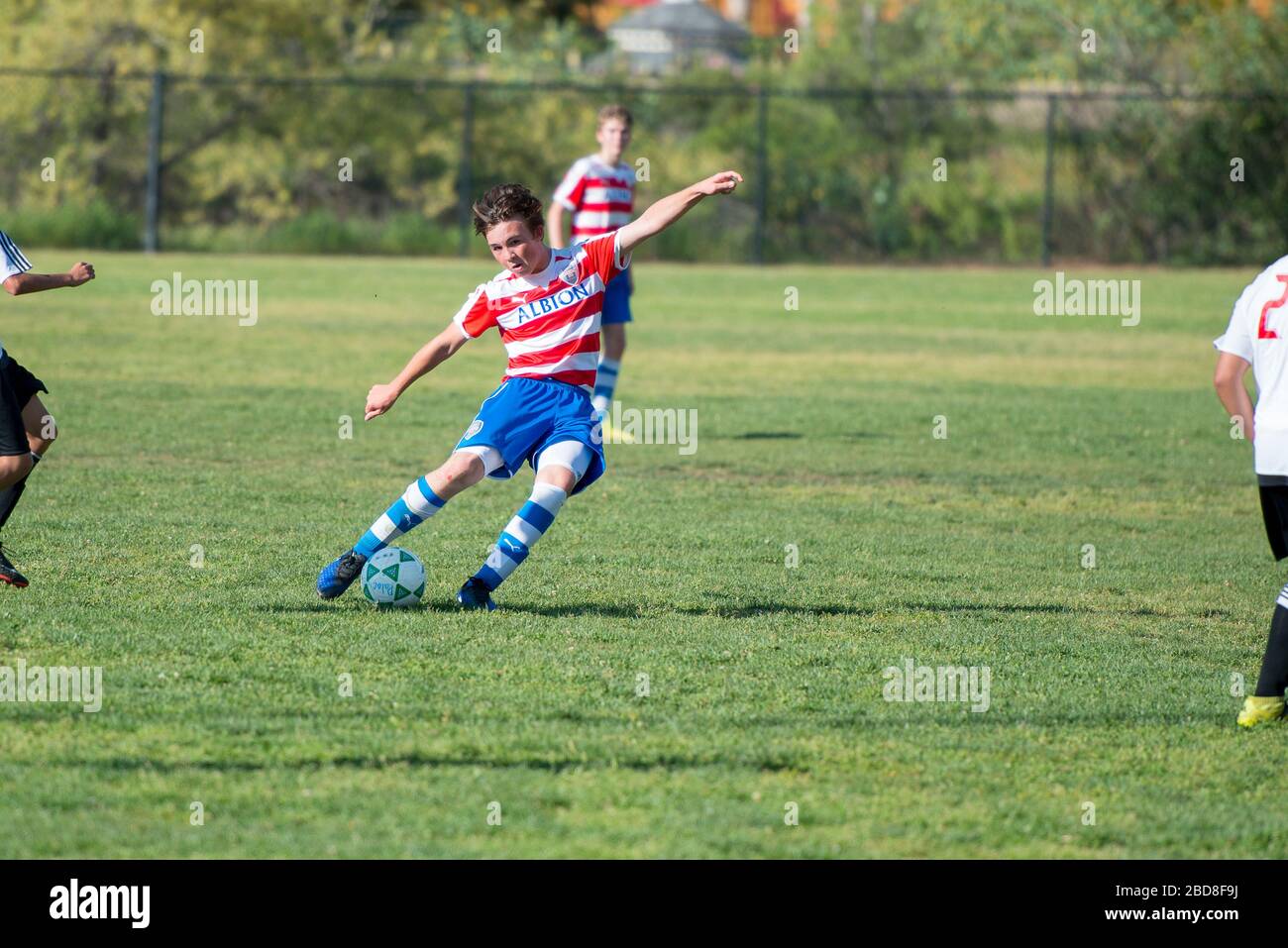 Teen giocatore di calcio in procinto di colpire la palla su un calcio libero Foto Stock