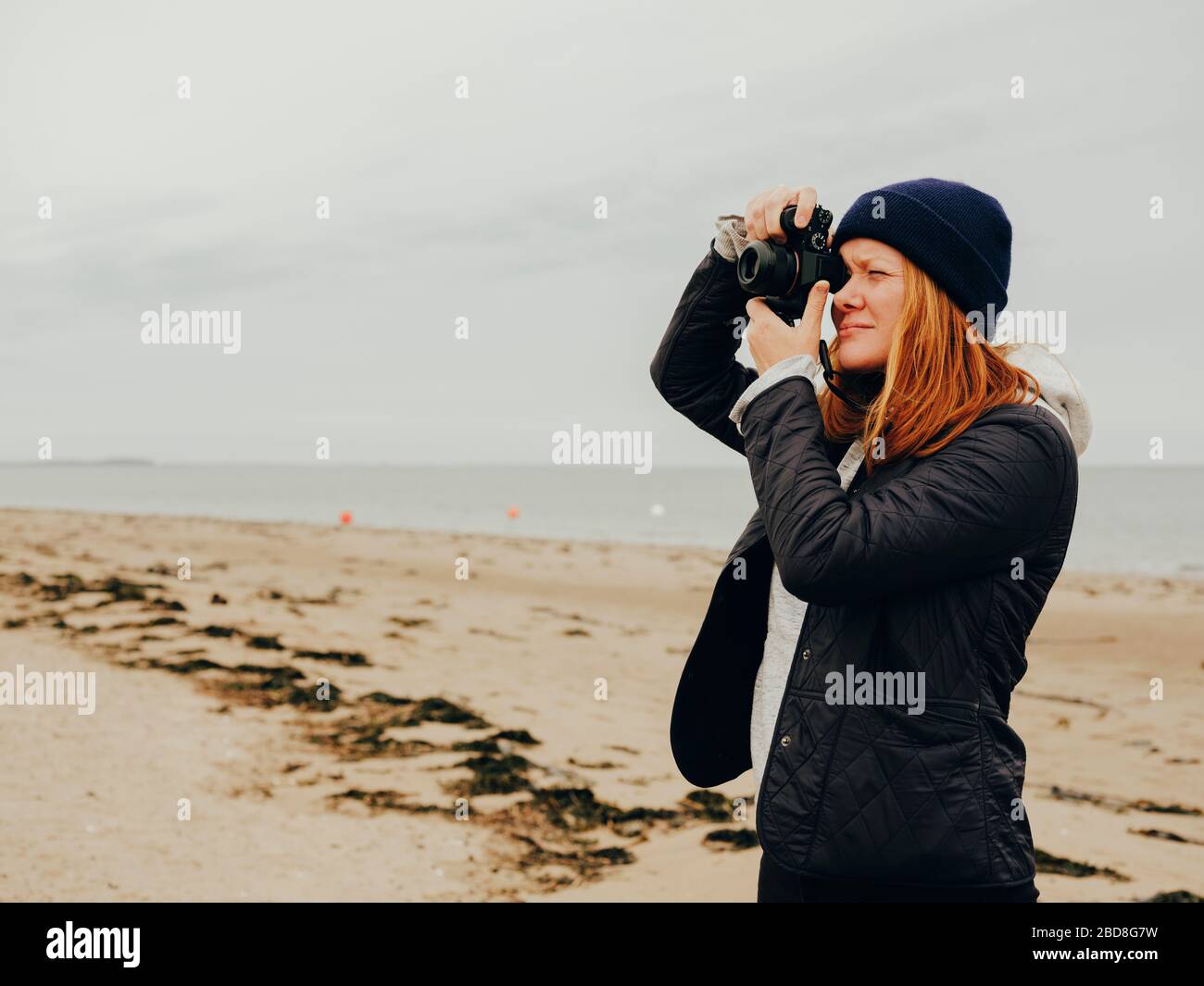Donna che scatta foto sulla spiaggia in Scozia Foto Stock
