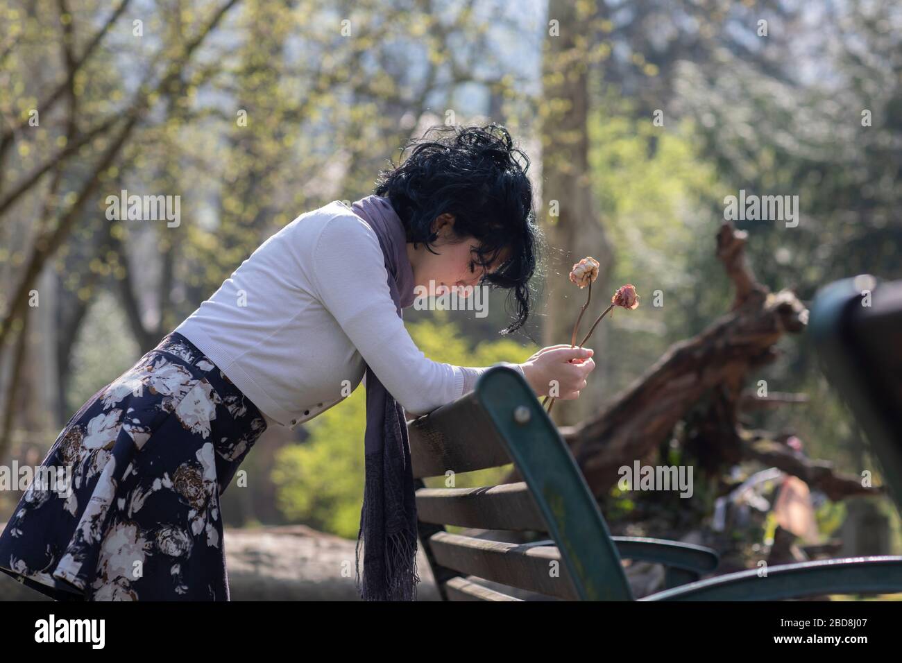 una donna in lutto che tiene le braccia su un panca del parco Foto Stock