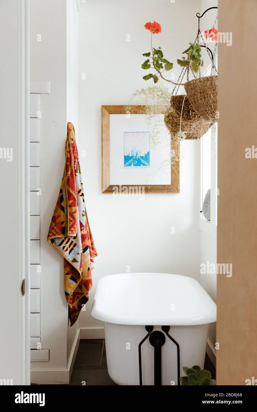 Fiore appeso, asciugamano Pendleton, e una vasca piede artiglio in bagno bianco Foto Stock