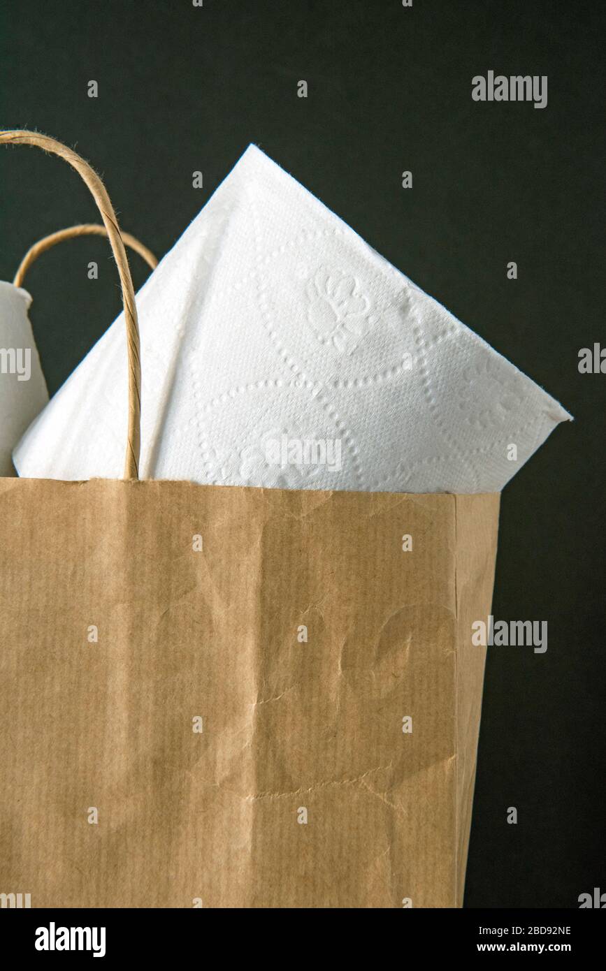 Carta igienica riciclata in rotoli, allentata nel sacchetto di supporto di carta marrone su sfondo nero. Concetto di zero sprechi Foto Stock