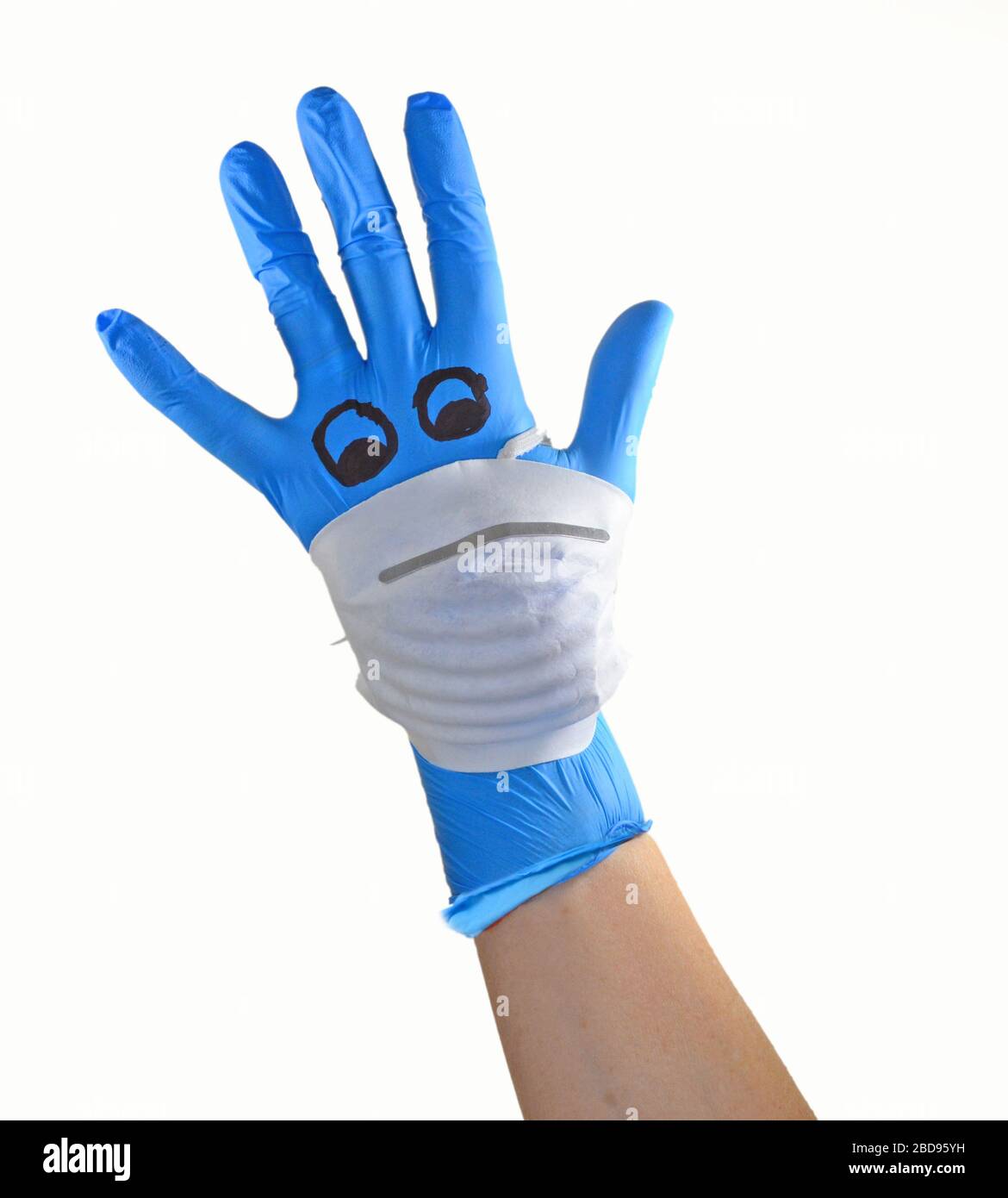 Mano con guanto chirurgico Blue con una maschera facciale raffigurante un viso con riferimento alla protezione medica contro il virus corona , covid 19. Foto Stock