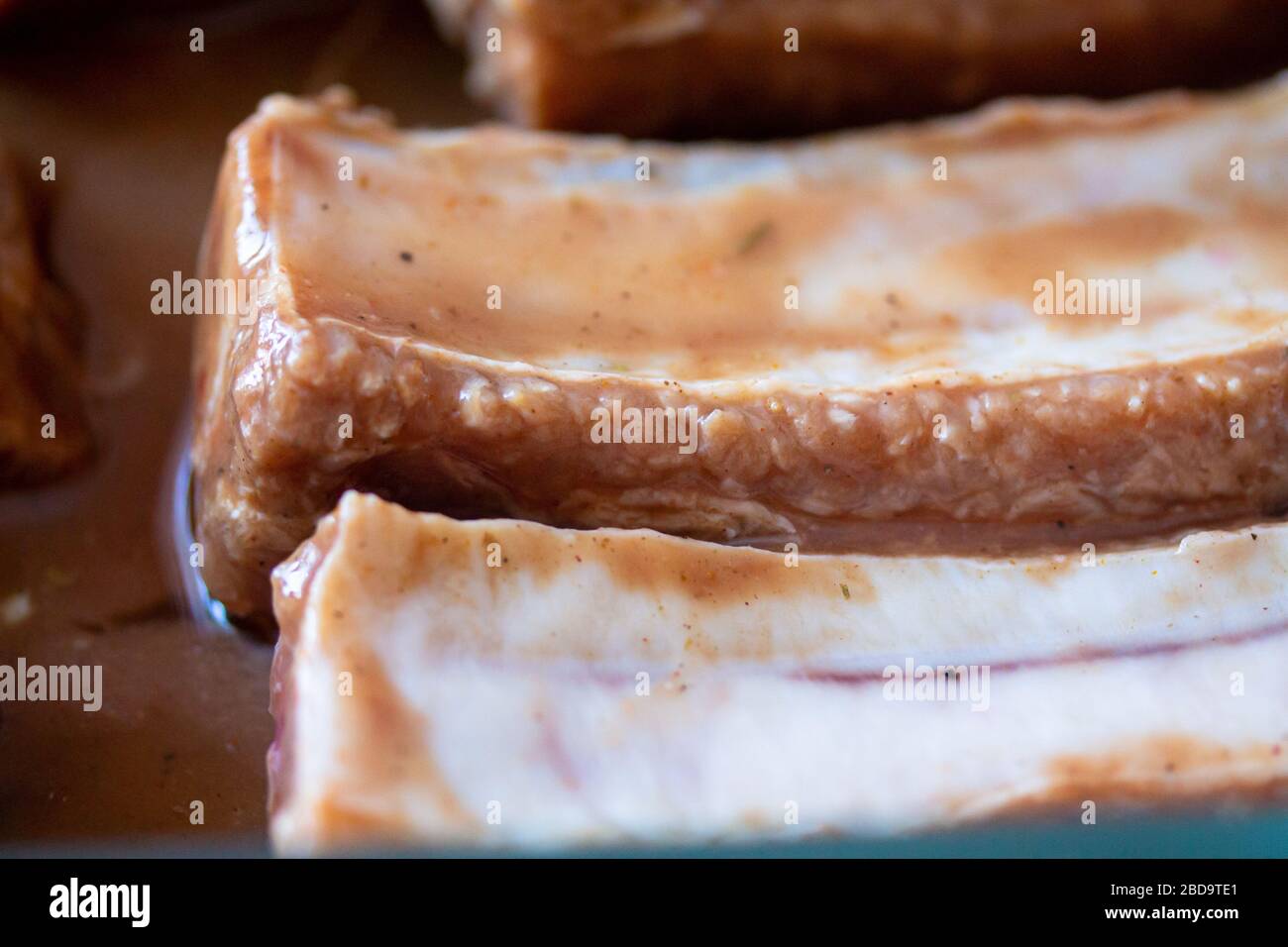 Costine di maiale crude e succose marinata pronte per la cottura. Immagine della lavorazione della carne. Fotografia di cibo sfondo primo piano Foto Stock