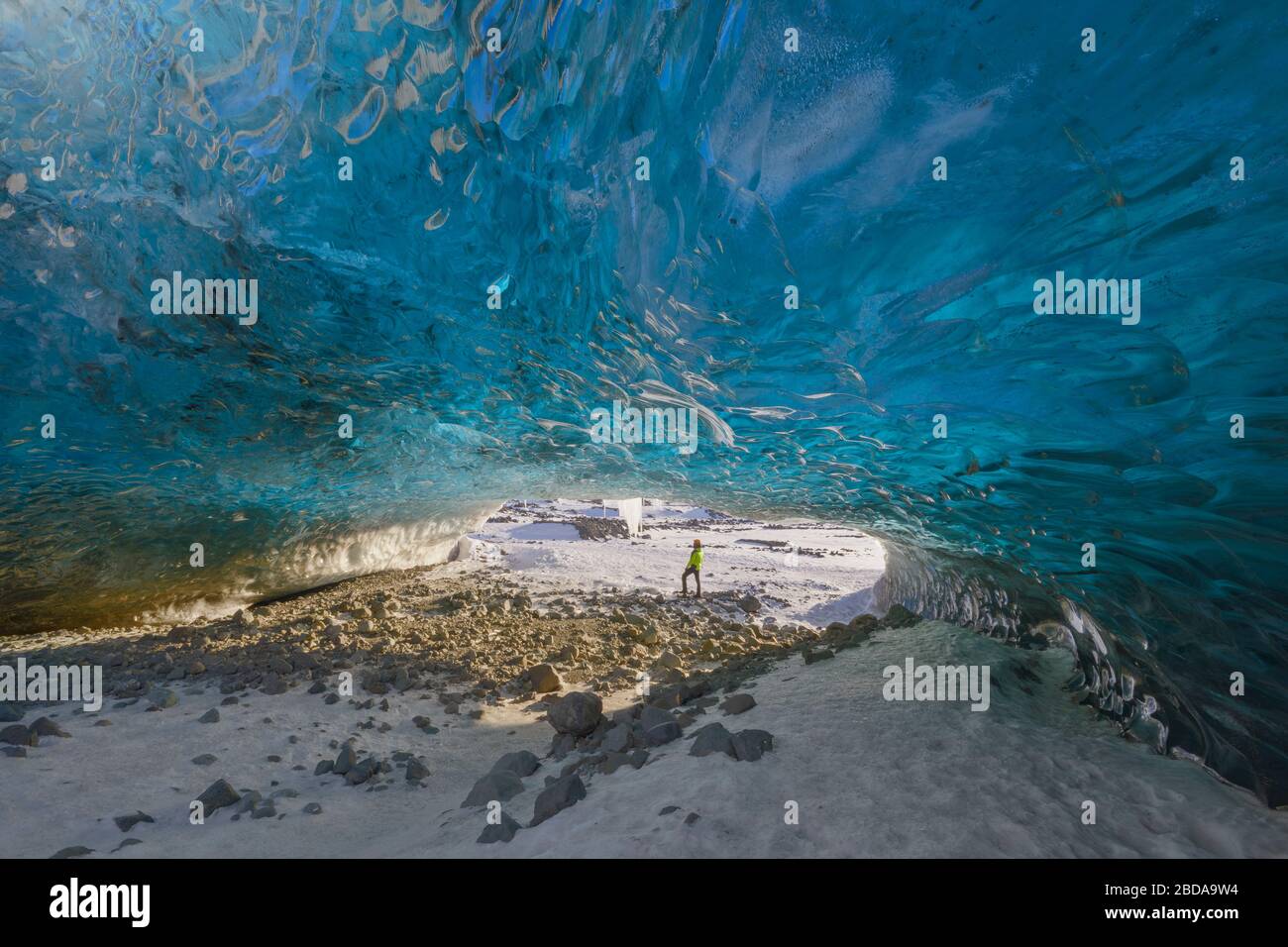 L'uomo si trova all'ingresso della grotta di ghiaccio di Breidamerkurjokull, Austurland, Islanda, Europa del Nord Foto Stock