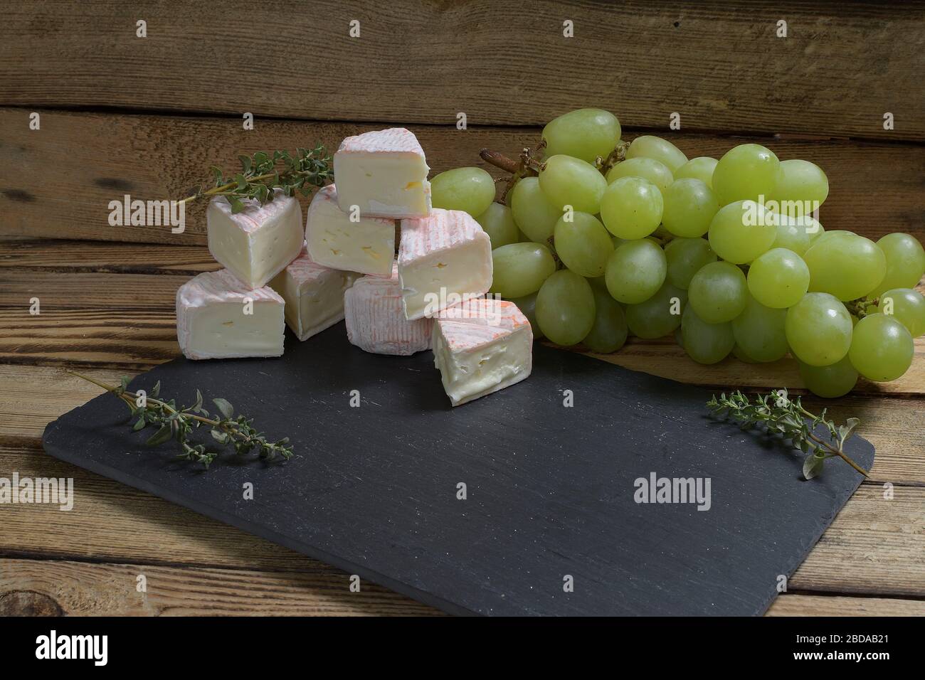 Frnch bianco formaggio muffa uva noci e un coltello formaggio su sfondo pietra Foto Stock