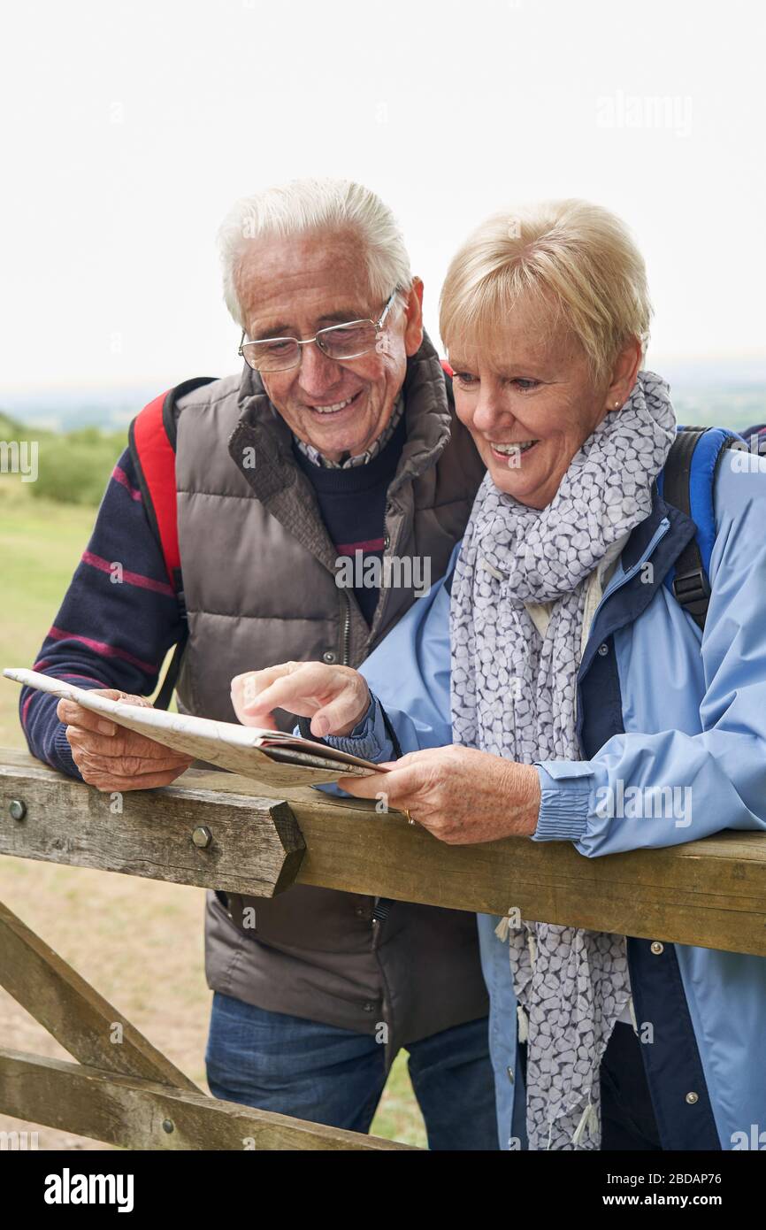 Senior pensionati Coppia in vacanza a piedi in appoggio sulla porta guardando alla mappa Foto Stock