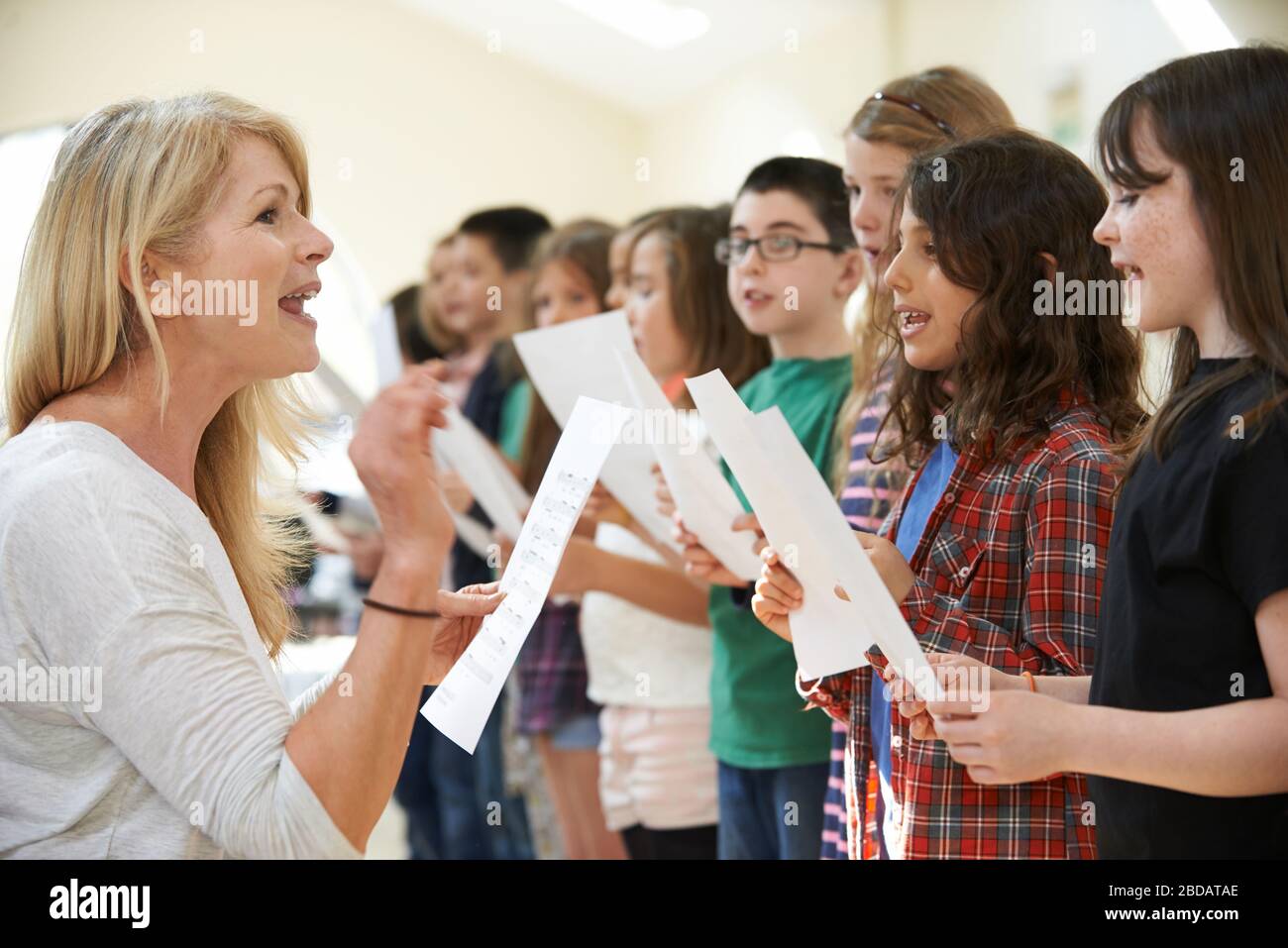 I bambini del Gruppo Singing sono incoraggiati dall'insegnante alla Scuola di Stage Foto Stock