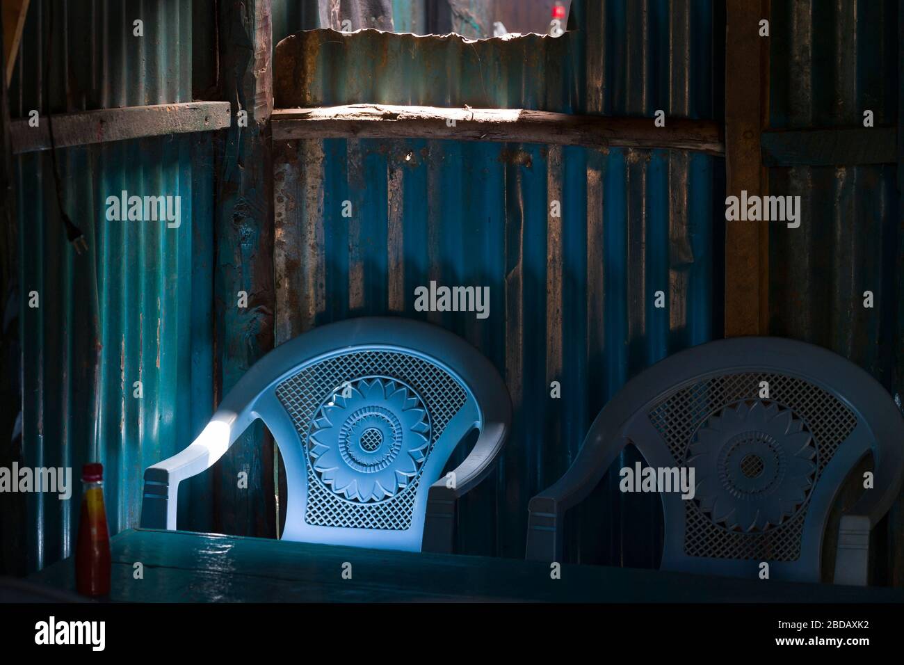 Due sedie di plastica in un caffè locale conosciuto come kibanda in Kenya, nel villaggio di Lusigetti che è circa 27 km a nord ovest del centro di Nairobi, in Foto Stock