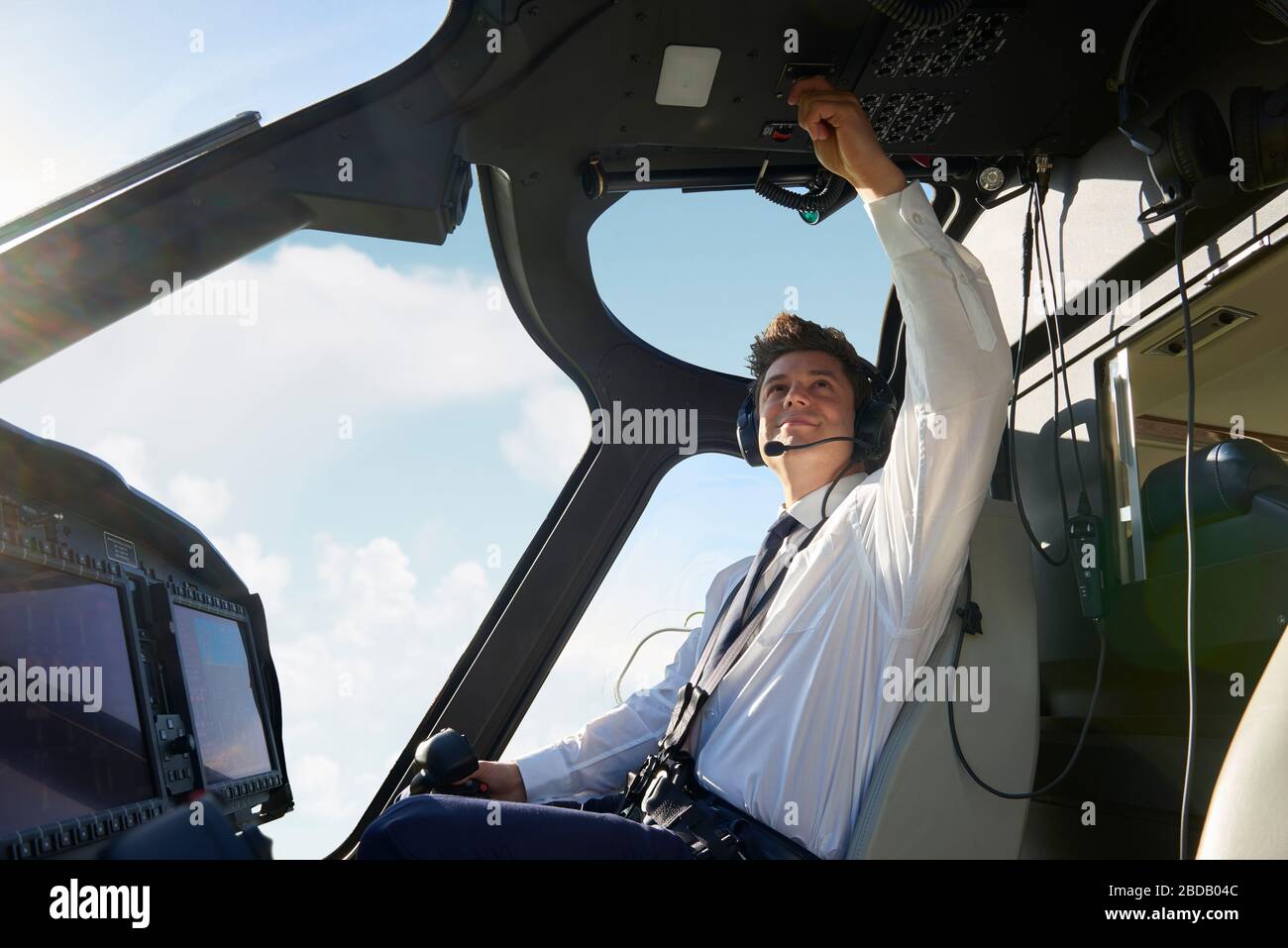 Pilota maschile in Cockpit of Helicopter facendo il controllo pre-volo prima del decollo Foto Stock