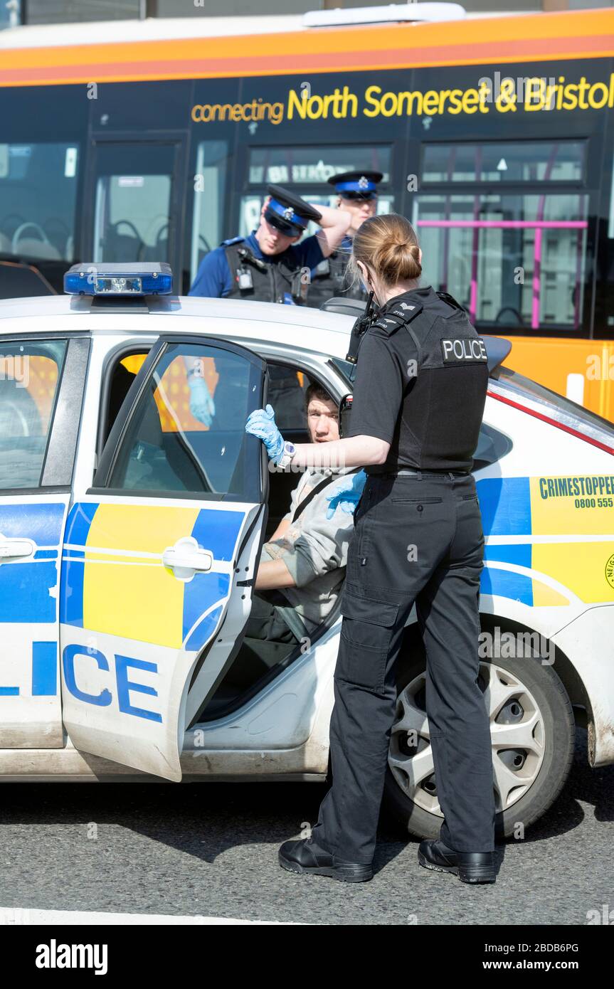 Una pattuglia di polizia con gli agenti di supporto della Comunità negozia con un uomo e lo ha messo in un'automobile di pattuglia a Weston-super-Mare durante il blocco di Coronavirus Foto Stock
