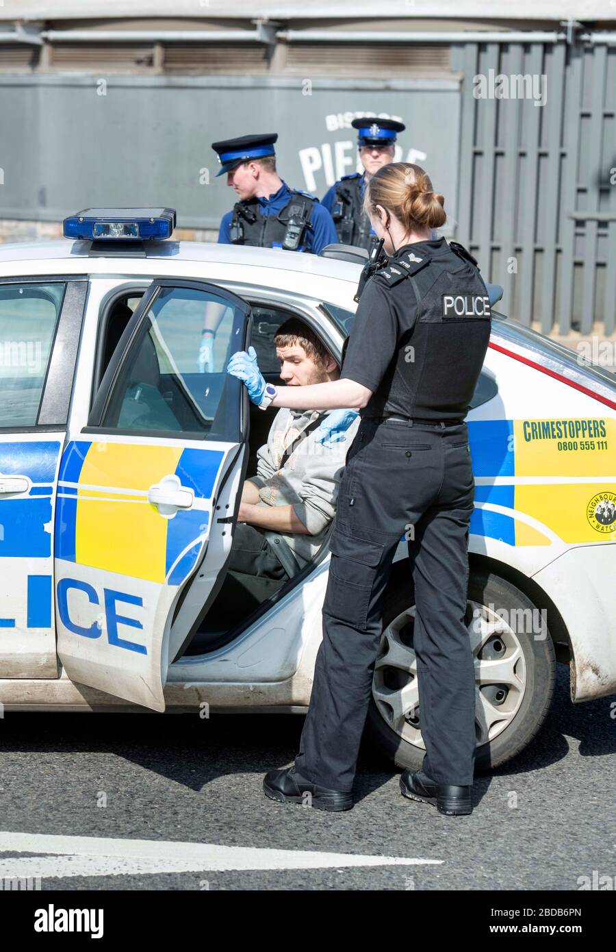 Una pattuglia di polizia con gli agenti di supporto della Comunità negozia con un uomo e lo ha messo in un'automobile di pattuglia a Weston-super-Mare durante il blocco di Coronavirus Foto Stock