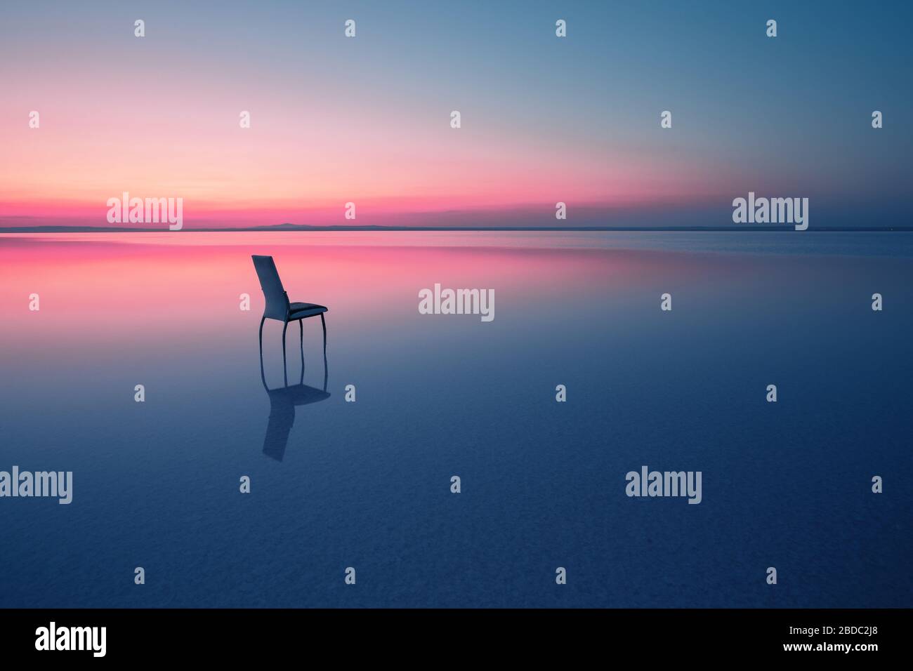 Sedia tra le acque lisce del lago al tramonto. Il concetto di solitudine e unità con la natura. Una sedia si trova nell'acqua del Salt Lake Ace. Anato Foto Stock