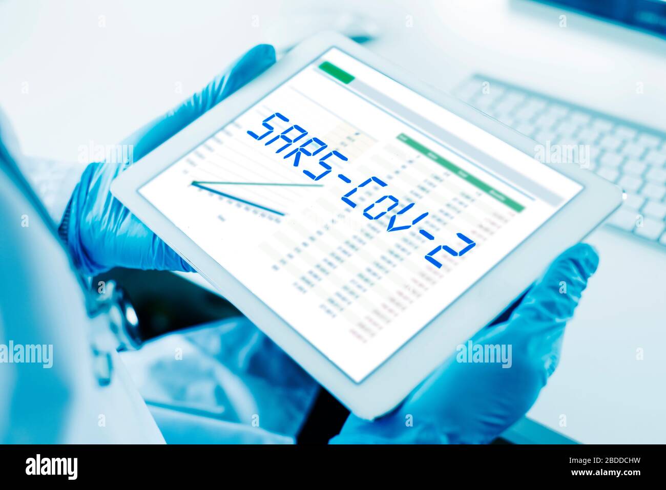Primo piano di un medico, indossando guanti chirurgici blu, con una tavoletta digitale in mano con il testo SARS-cov-2 nel suo schermo Foto Stock