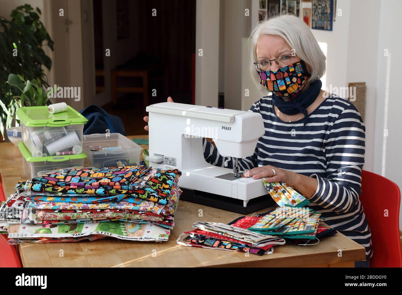 25.03.2020, Berlino, , Germania - Retiree sews i moutguards del tessuto nel suo soggiorno a causa delle strozzature di consegna in tempi della crisi di Corona. 00S20032 Foto Stock