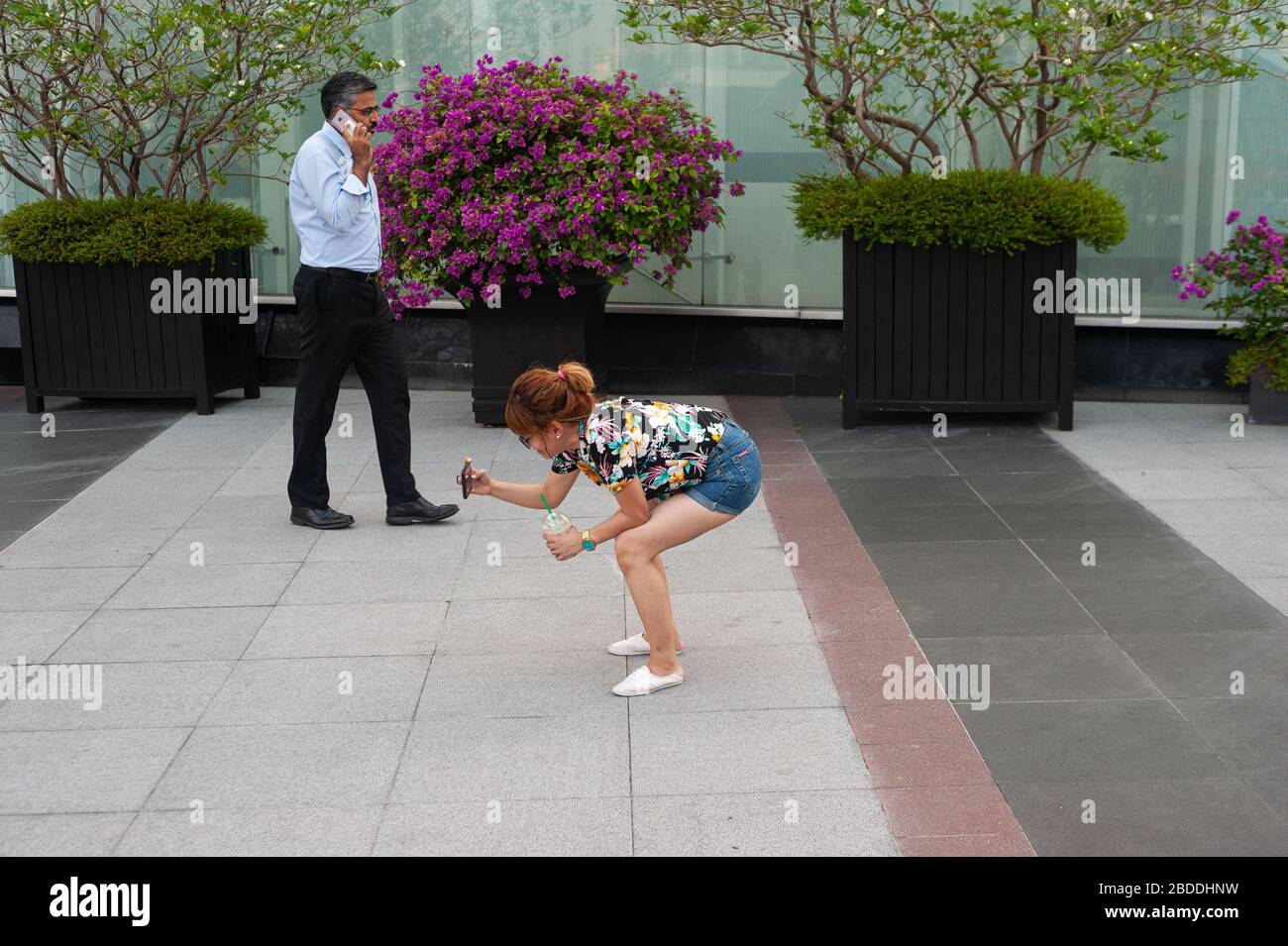 06.09.2019, Singapore, , Singapore - una donna si accovaccia e scatta foto a Marina Bay mentre un uomo è al telefono sullo sfondo. 0SL190906D001CAROE Foto Stock