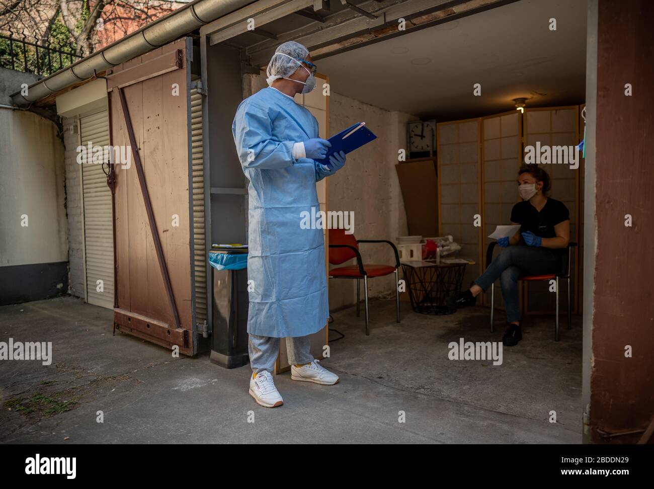 Berlino, Germania. 8 aprile 2020. Jose Persez, intern, parla al paziente Clara prima di effettuare un test su di lei per il coronavirus, in un garage nel cortile del medico di Kreuzberg. Il dottor Beate Krupp ed i suoi colleghi hanno deciso di effettuare il test su tutti i pazienti che lo desiderano. Per non gravare la pratica con questo, il sito di smear temporaneo è stato istituito nel garage, che è altrimenti utilizzato come deposito per la pratica. Credit: Michael Kappeler/dpa/Alamy Live News Foto Stock