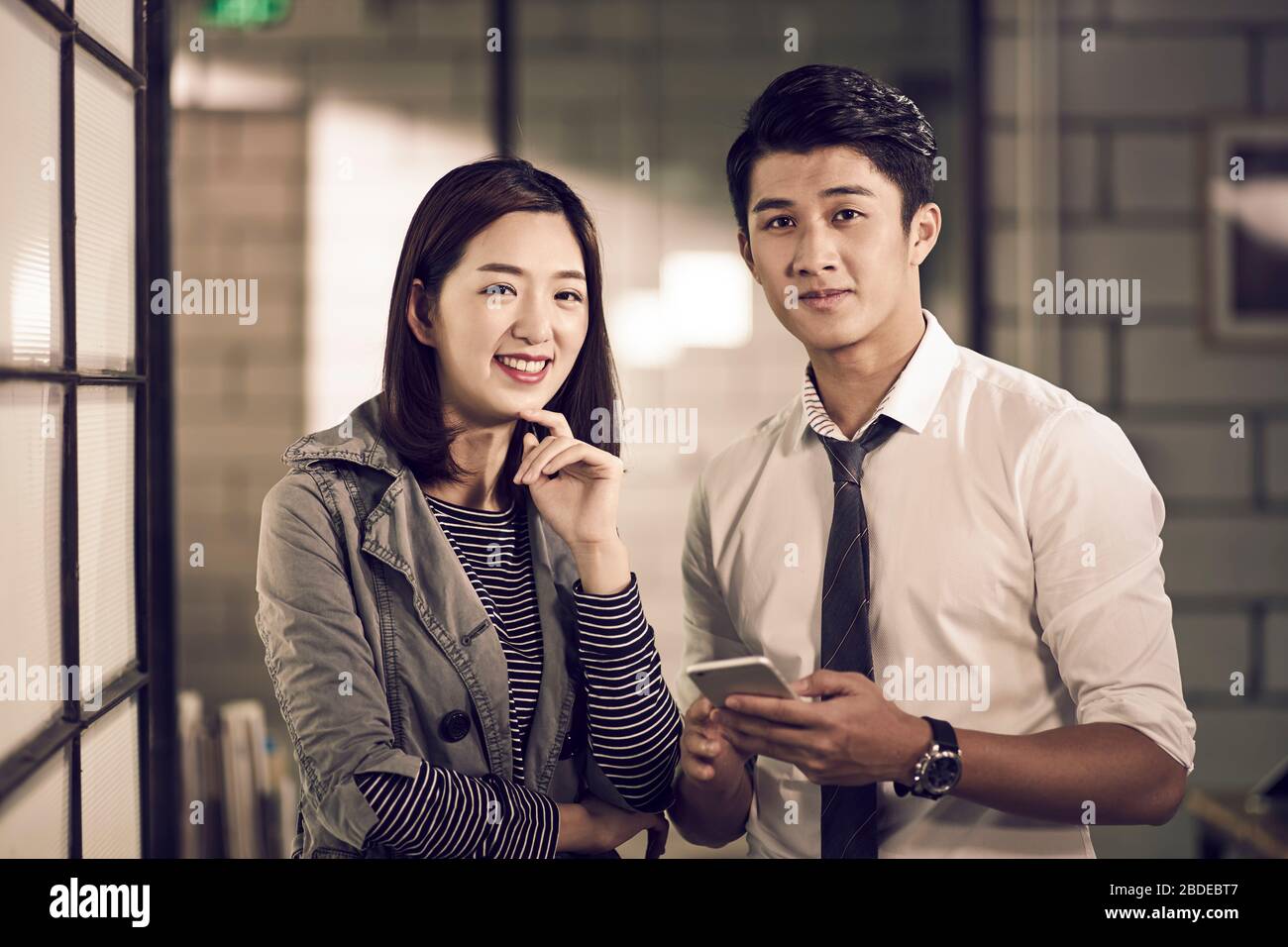 ritratto di giovani imprenditori asiatici businessman e businesswoman guardando macchina fotografica sorridente Foto Stock
