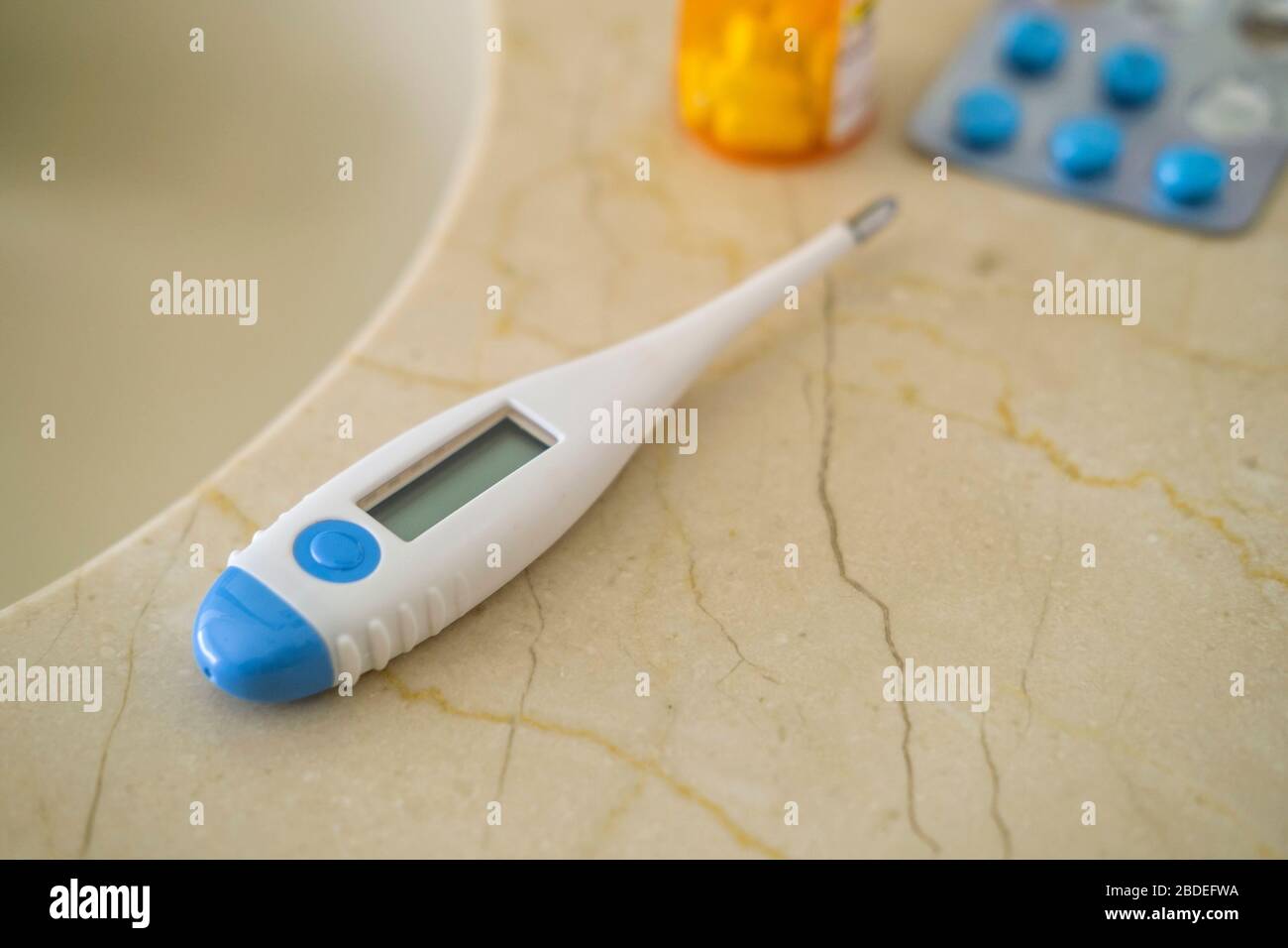 Termometro e pillole su superficie di pietra Foto Stock