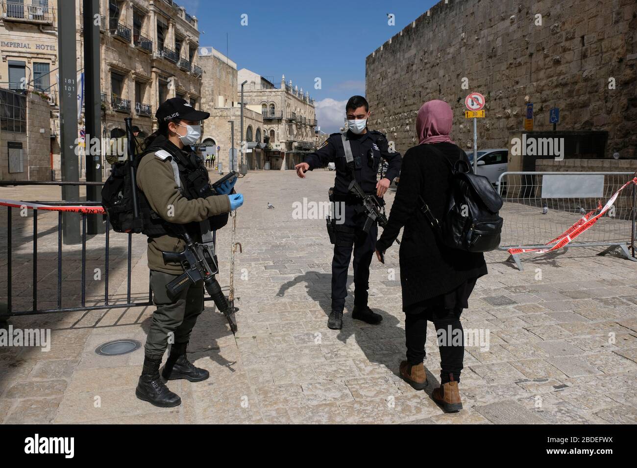 Polizia di frontiera israeliana con maschera protettiva che controlla l'identità di una donna araba israeliana in un checkpoint situato nella città vecchia di Gerusalemme durante lo scoppio della malattia di coronavirus (COVID-19) in Israele. Foto Stock