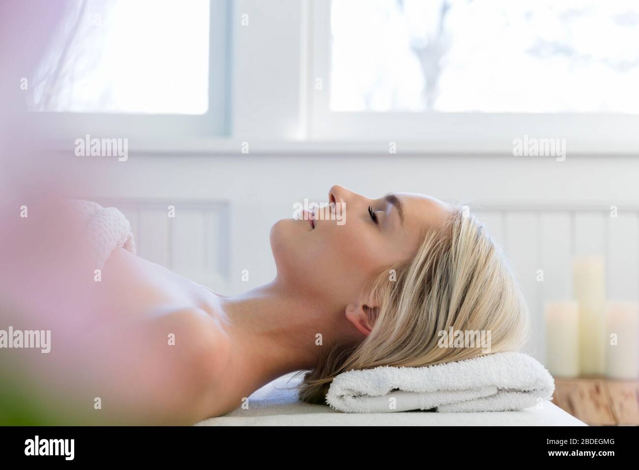 Donna sdraiata sulla schiena sul tavolo da massaggio con gli occhi chiusi Foto Stock