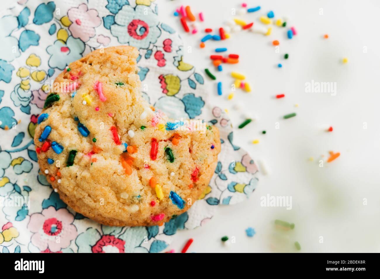 Biscotti fatti in casa con coloratissima spruzzatura su tovagliolo floreale Foto Stock