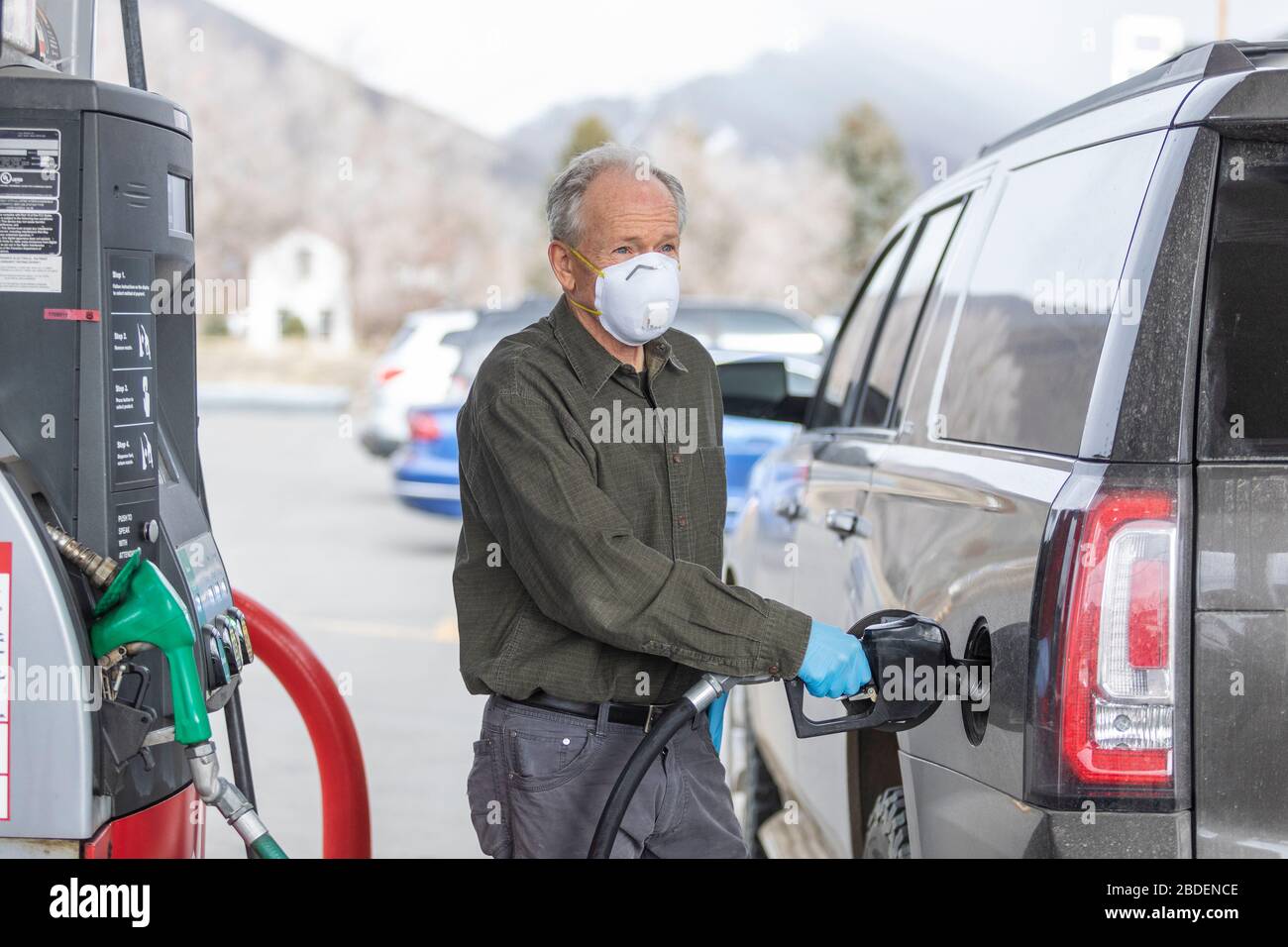 Uomo che indossa guanti chirurgici e maschera di rifornimento auto a gas stazione Foto Stock