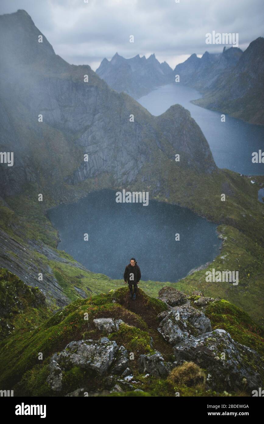 Norvegia, Isole Lofoten, Reine, Man sulla montagna di Reinebringen con lago e fiordo sullo sfondo Foto Stock